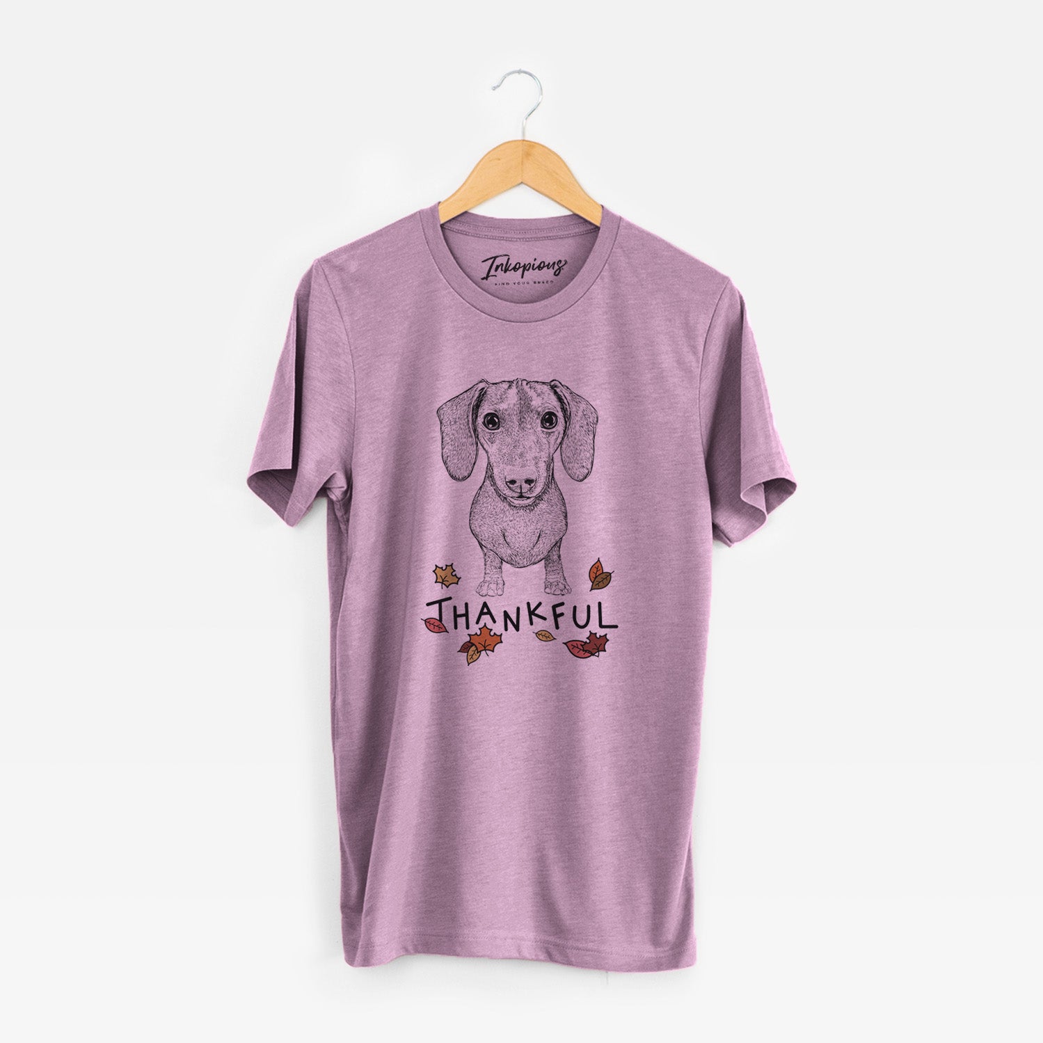 Hand-drawn sketch of Ernie the Mini Dachshund with 'Thankful' lettering and autumn leaves on an Orchid Unisex crewneck