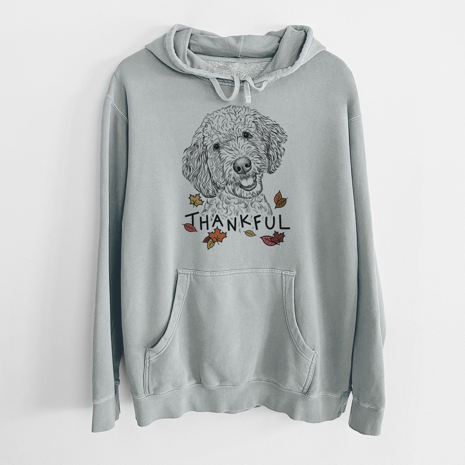 Hand-drawn sketch of Gizmo the Goldendoodle with 'Thankful' lettering and autumn leaves on a Sage Unisex pigment dyed hoodie