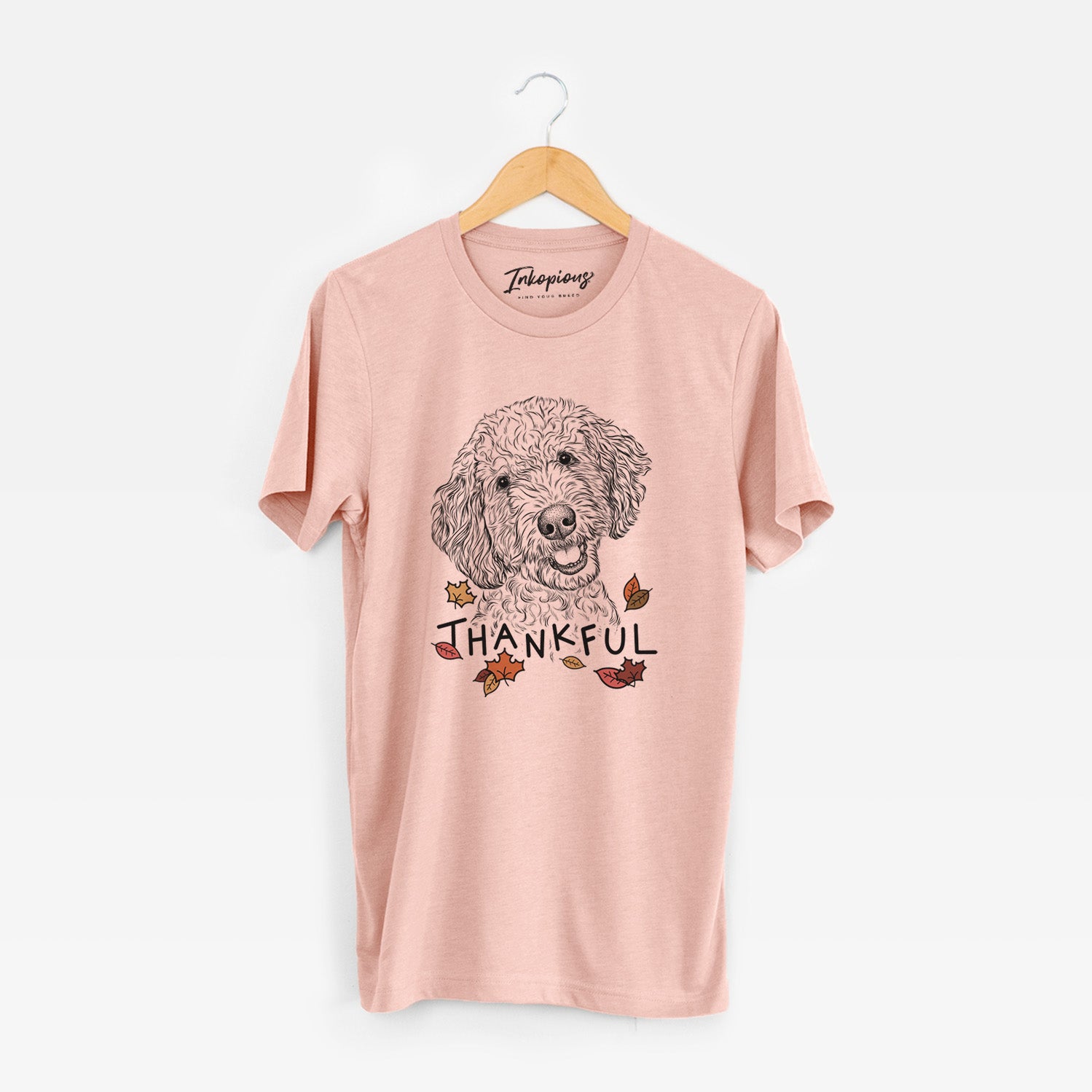 Hand-drawn sketch of Gizmo the Goldendoodle with 'Thankful' lettering and autumn leaves on a Peach Unisex crewneck