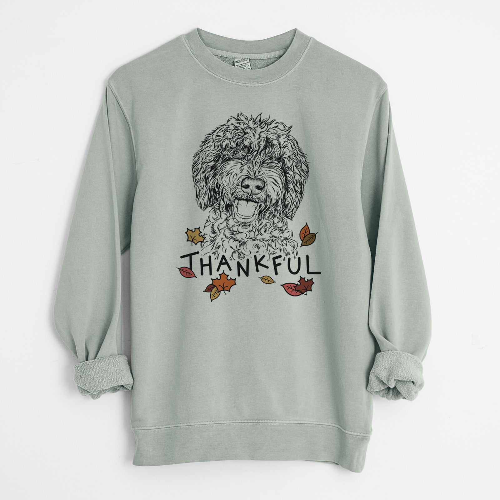 Hand-drawn sketch of Jack the Chocolate Labradoodle with 'Thankful' lettering and autumn leaves on a Sage Unisex pigment dyed crew sweatshirt