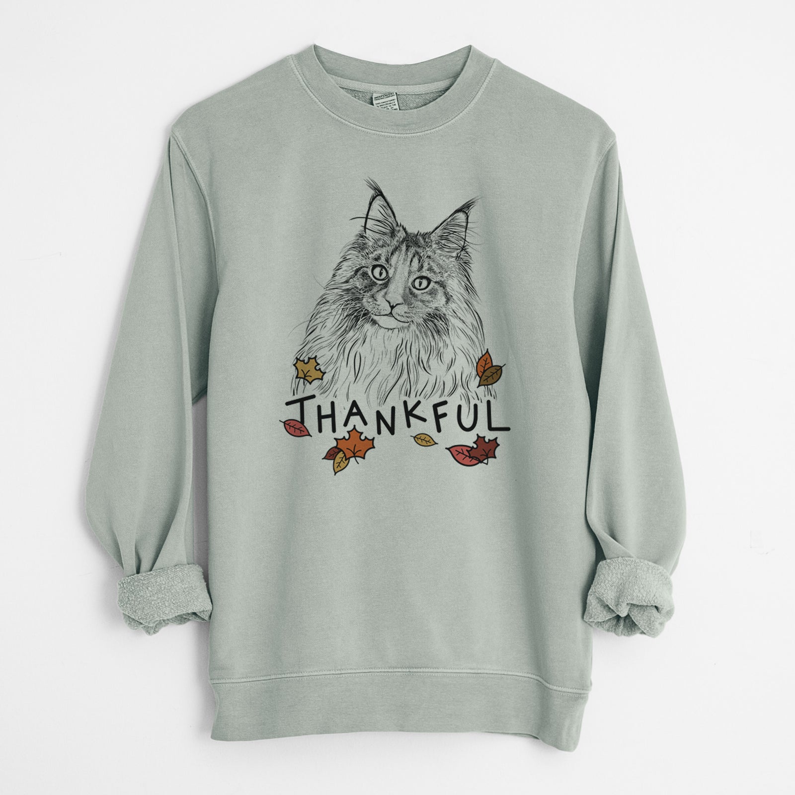 Hand-drawn sketch of Kiki the Maine Coon Cat with 'Thankful' lettering and autumn leaves on a Sage Unisex pigment dyed crew sweatshirt