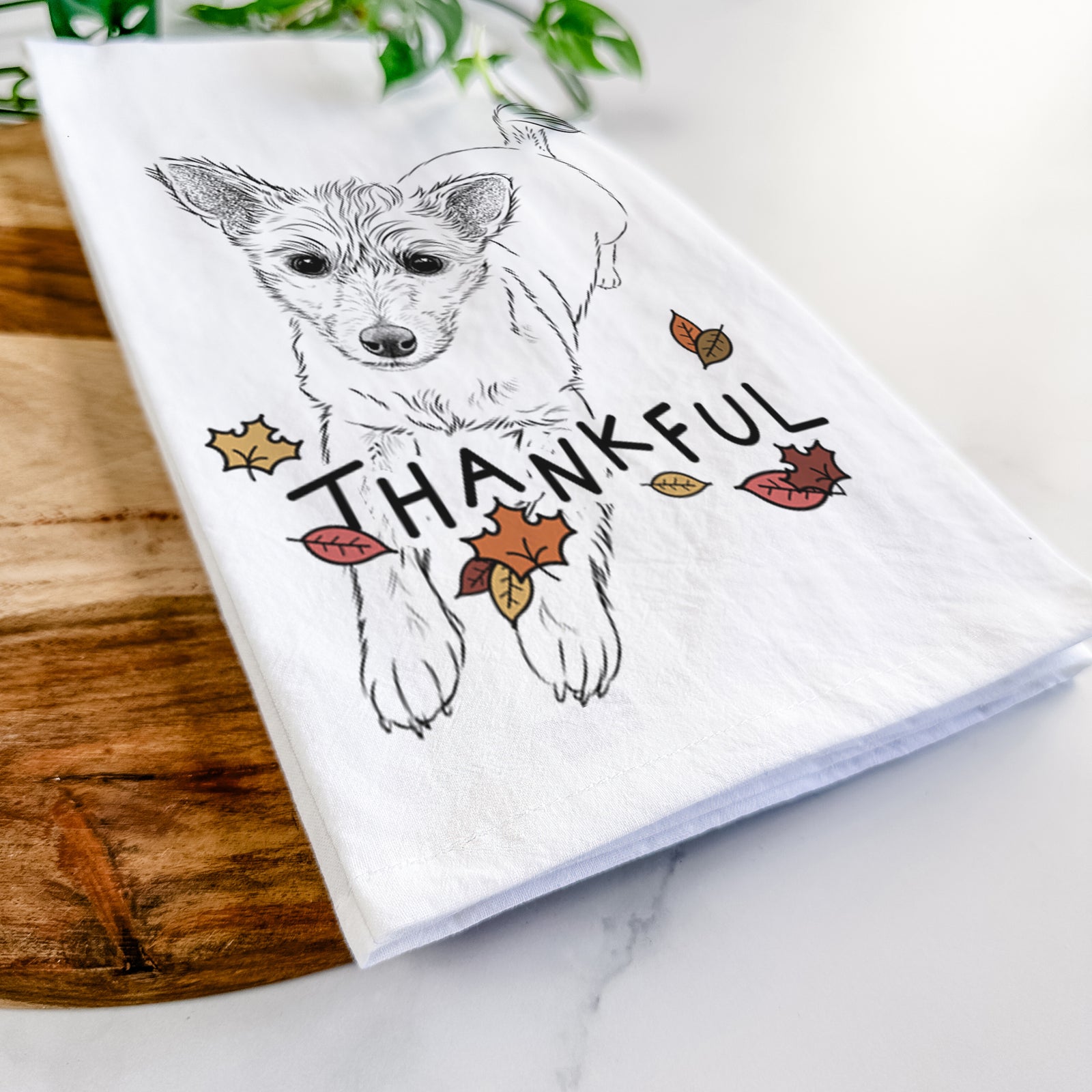 Hand-drawn sketch of Maisie the Terrier Mix with 'Thankful' lettering and autumn leaves on a tea towel