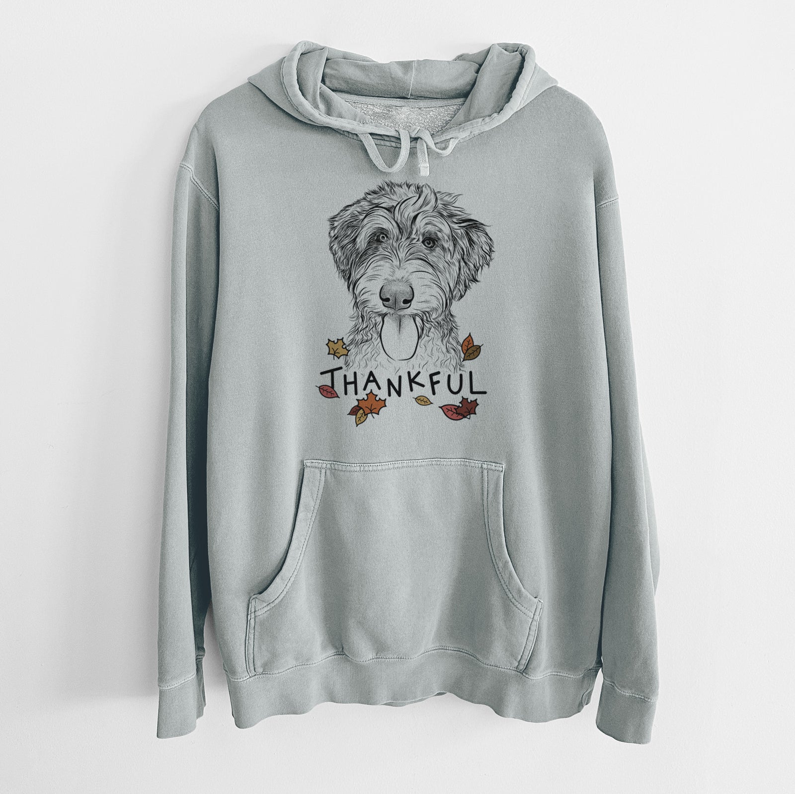 Hand-drawn sketch of Myrtle Mae the Aussiedoodle with 'Thankful' lettering and autumn leaves on a Sage Unisex pigment dyed hoodie