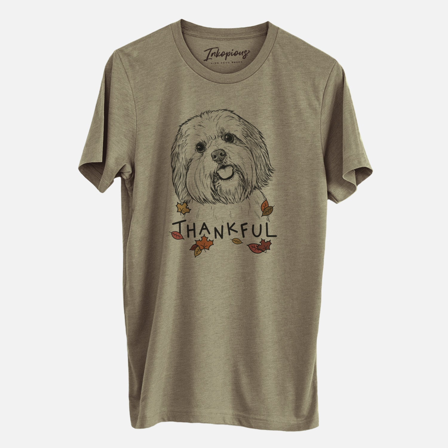 Hand-drawn sketch of Nikka the Lowchen with 'Thankful' lettering and autumn leaves on an Olive Unisex crewneck, worn by a man