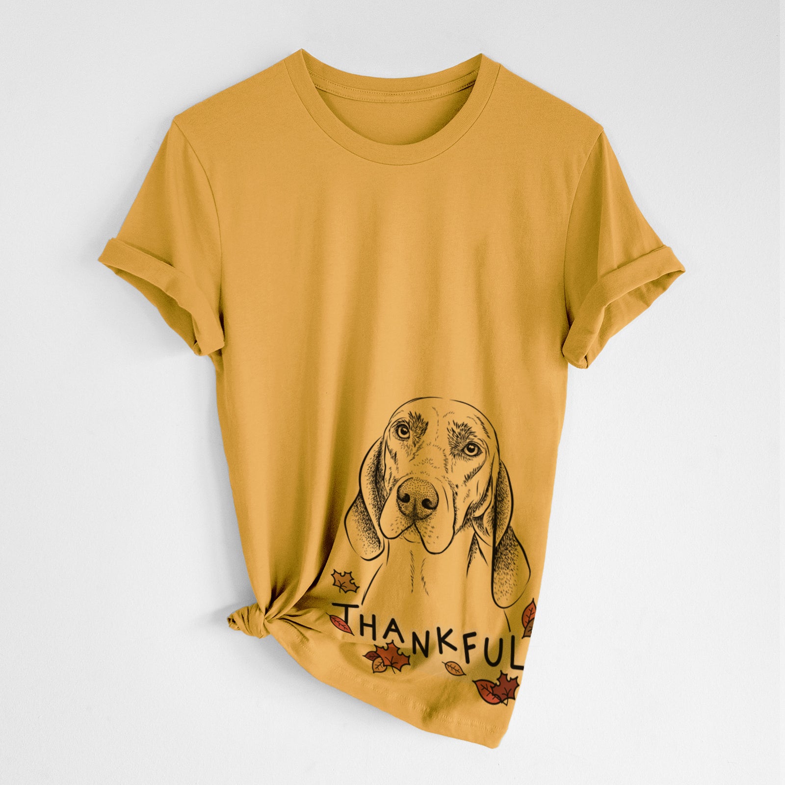 Hand-drawn sketch of Norman the Plott Hound with 'Thankful' lettering and autumn leaves on a Mustard Unisex crewneck, worn by a woman