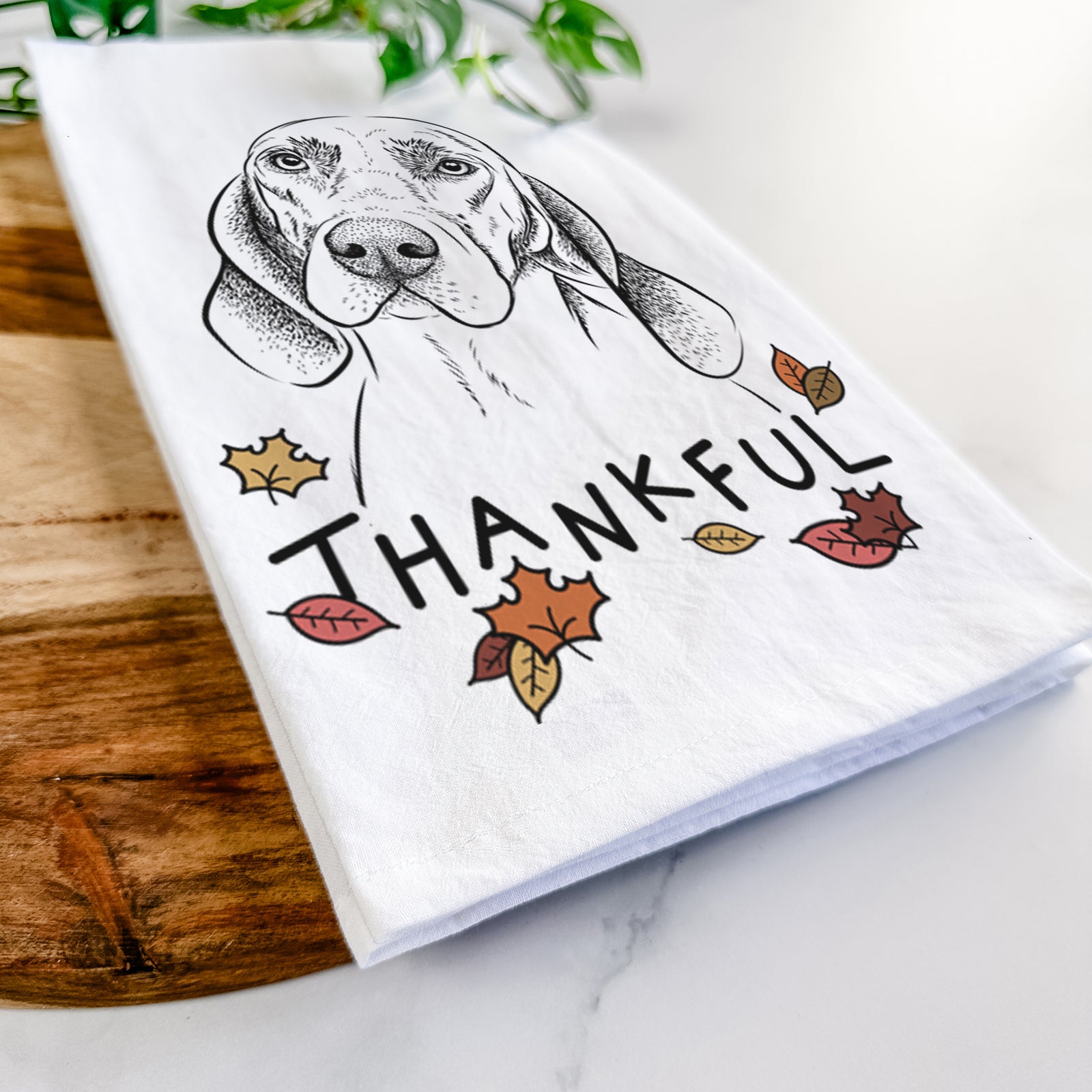 Hand-drawn sketch of Norman the Plott Hound with 'Thankful' lettering and autumn leaves on a tea towel