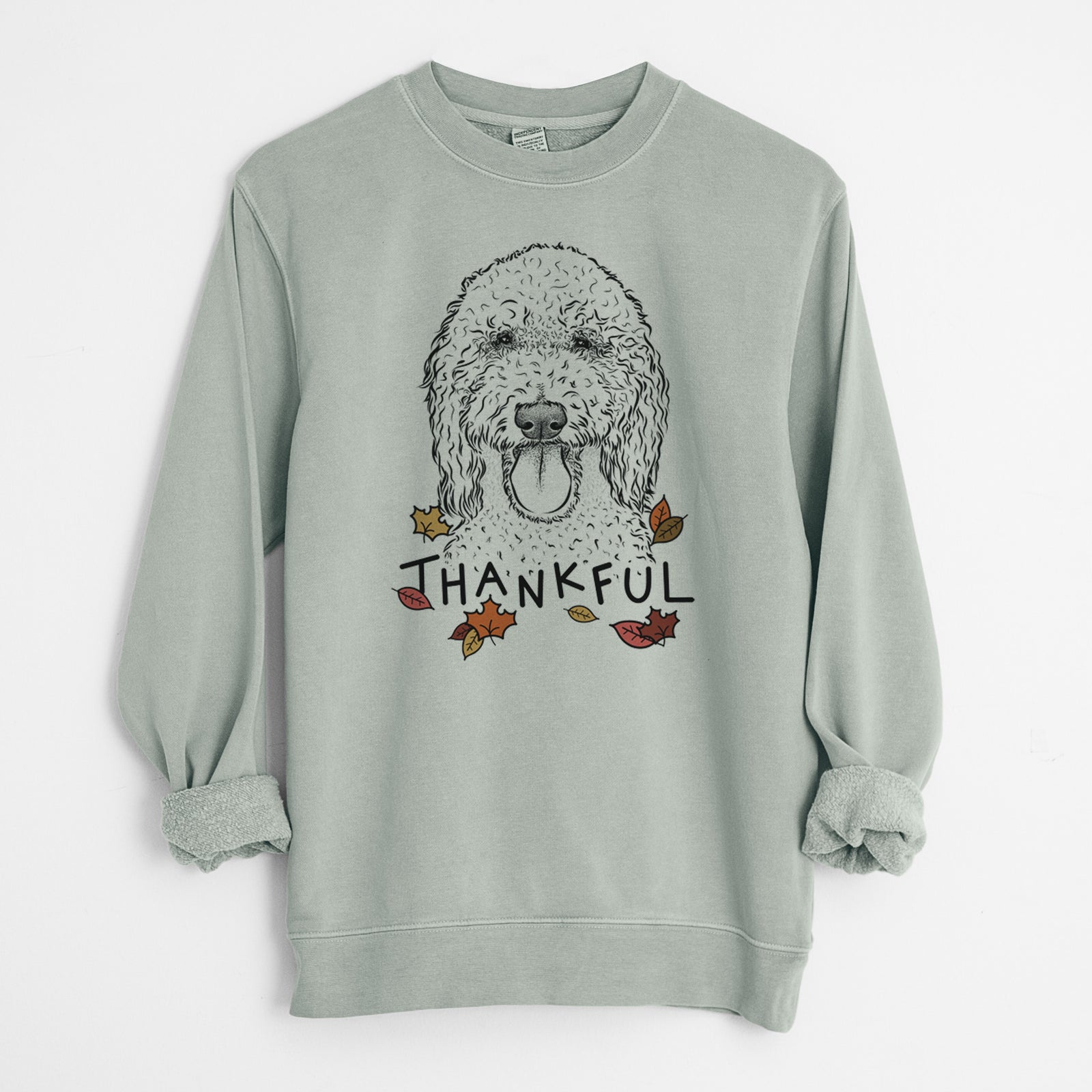 Hand-drawn sketch of Pavlov the Goldendoodle with 'Thankful' lettering and autumn leaves on a Sage Unisex pigment dyed crew sweatshirt