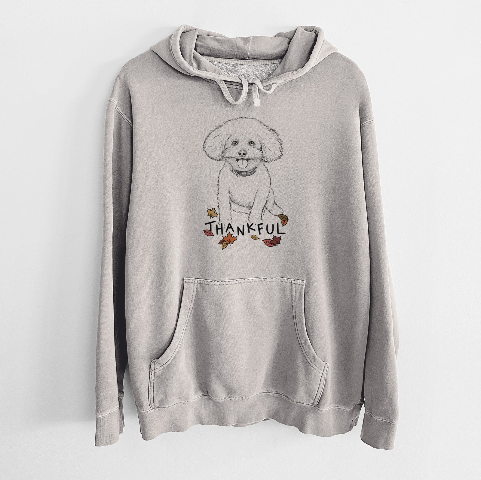 Hand-drawn sketch of Peyton the Bichon Frise with 'Thankful' lettering and autumn leaves on a Cement Unisex pigment dyed hoodie