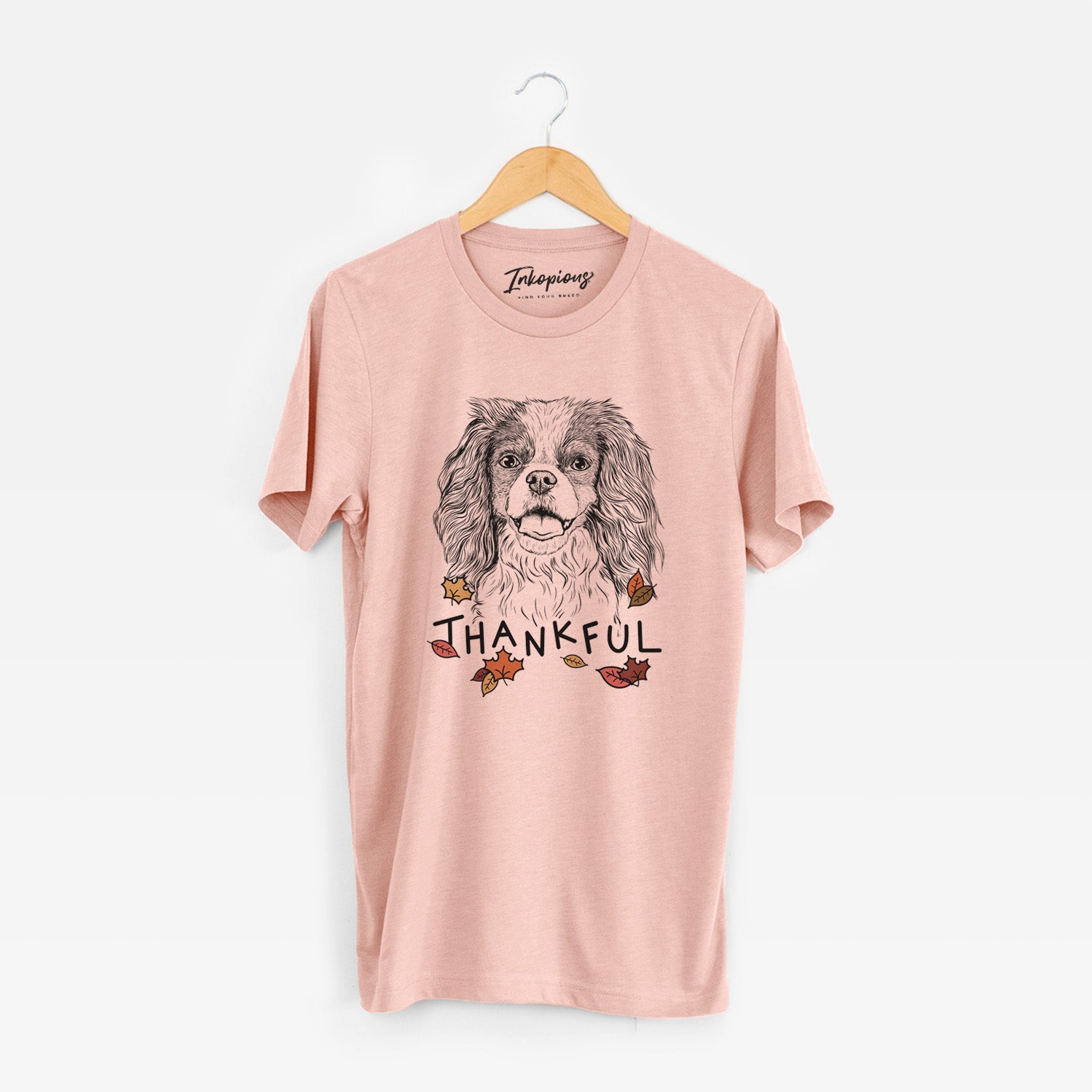 Hand-drawn sketch of Poppy the Cavalier King Charles Spaniel with 'Thankful' lettering and autumn leaves on a Peach Unisex crewneck