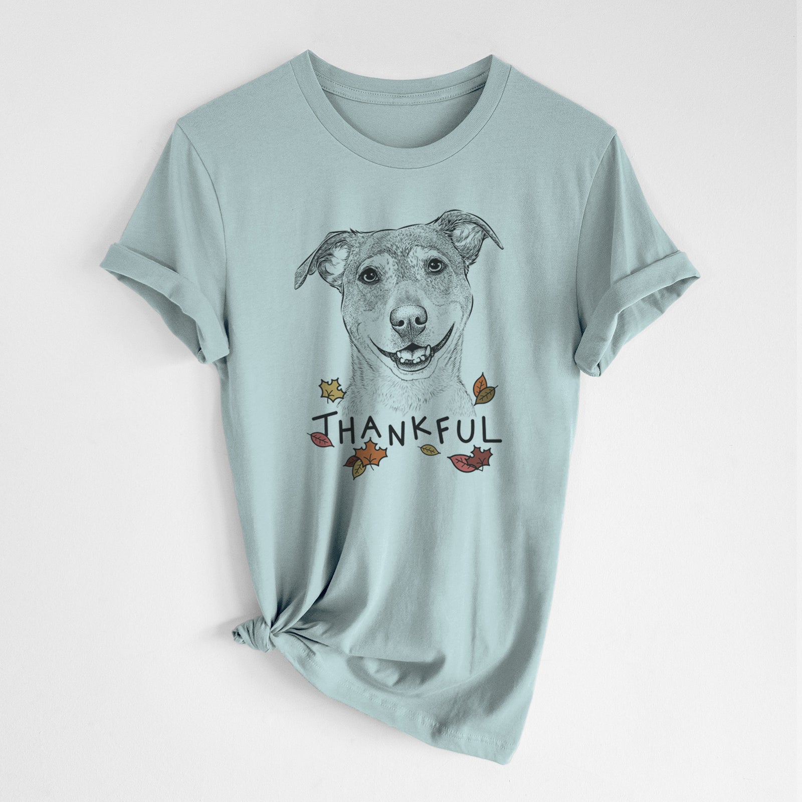 Hand-drawn sketch of Reese the Mountain Cur with 'Thankful' lettering and autumn leaves on a Dusty Blue Unisex crewneck, worn by a woman