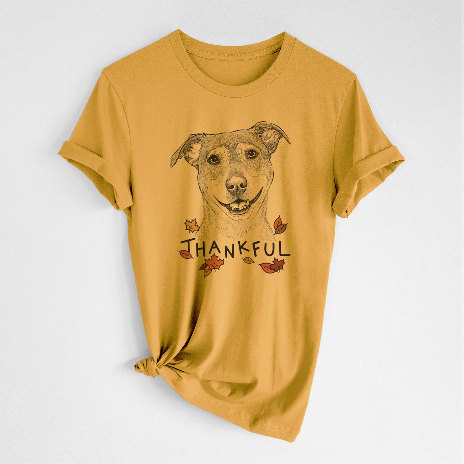 Hand-drawn sketch of Reese the Mountain Cur with 'Thankful' lettering and autumn leaves on a Mustard Unisex crewneck, worn by a woman
