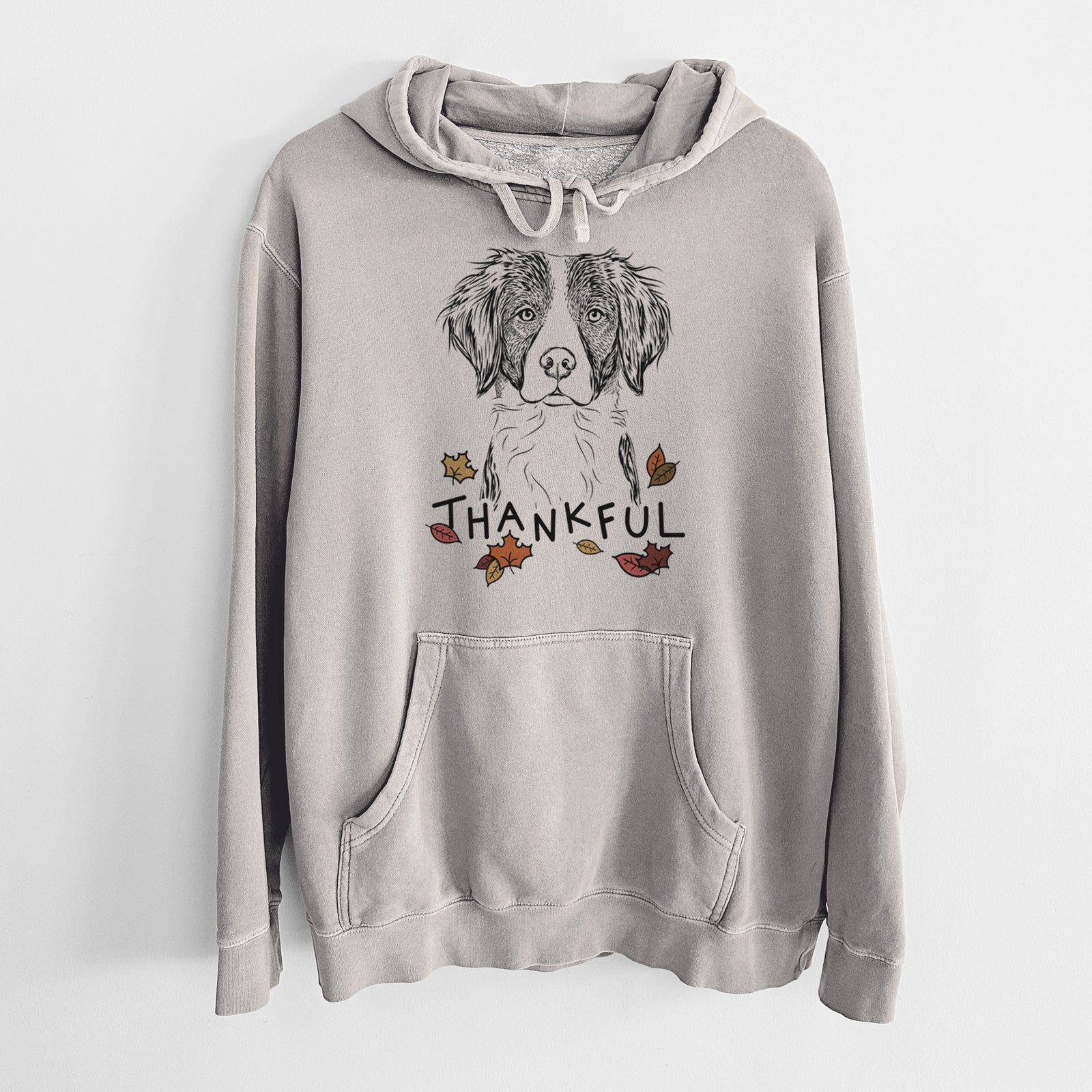 Hand-drawn sketch of Remi the Brittany with 'Thankful' lettering and autumn leaves on a Cement Unisex pigment dyed hoodie
