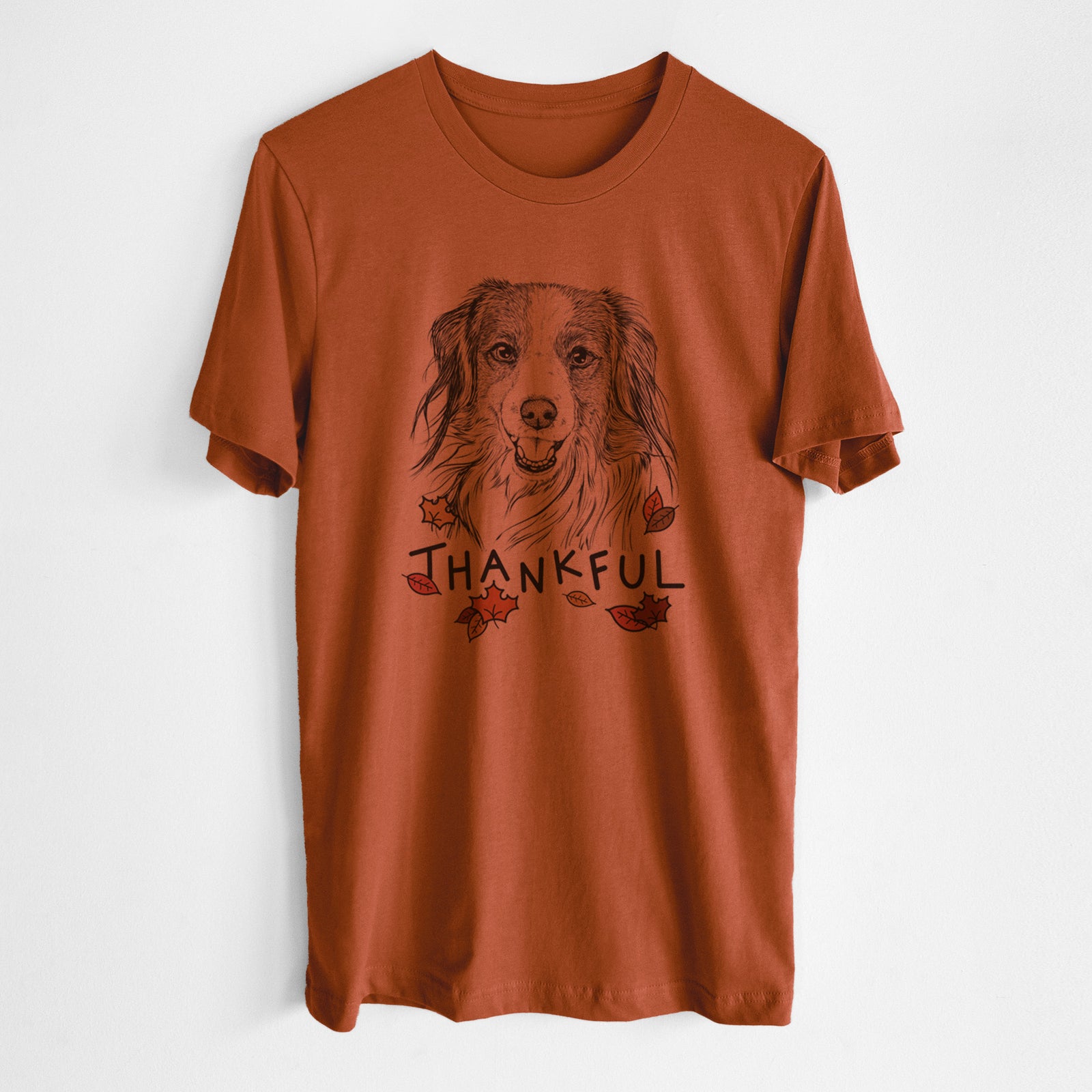 Hand-drawn sketch of Rutger the Nederlandse Kooikerhondje with 'Thankful' lettering and autumn leaves on an Autumn Unisex crewneck, worn by a man