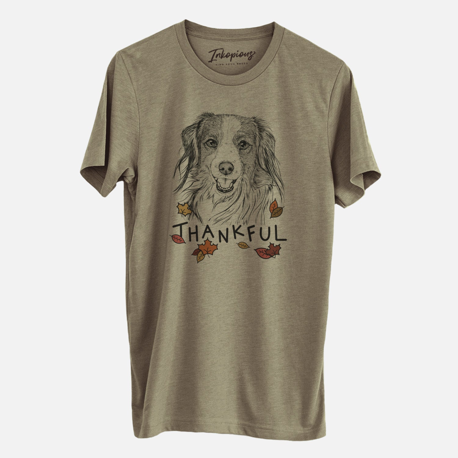 Hand-drawn sketch of Rutger the Nederlandse Kooikerhondje with 'Thankful' lettering and autumn leaves on an Olive Unisex crewneck, worn by a man