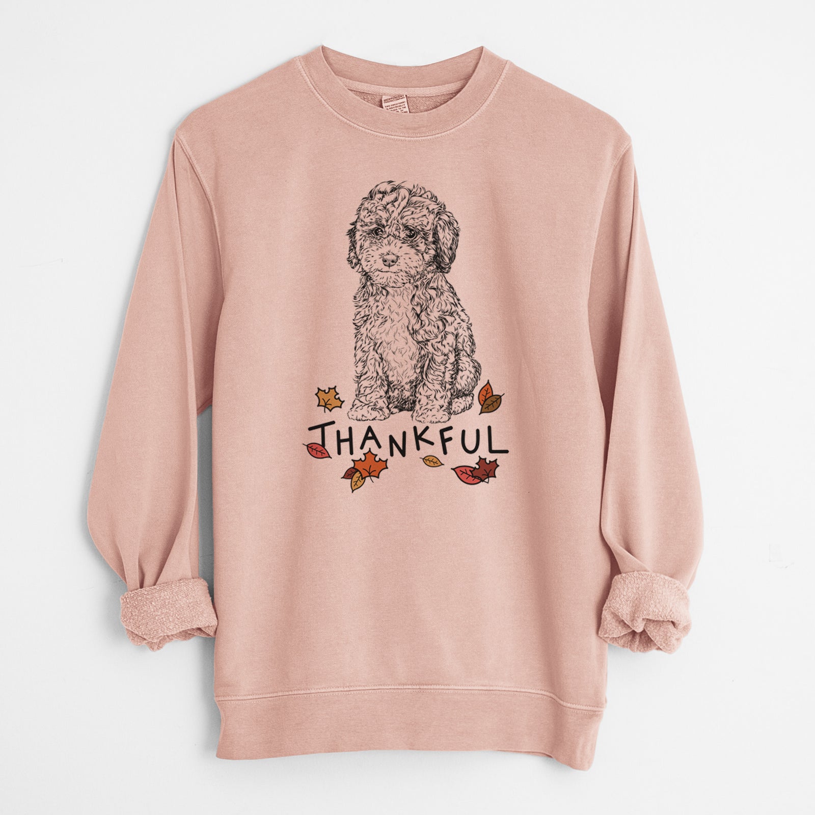 Hand-drawn sketch of Sweet Tea the Mini Doodle with 'Thankful' lettering and autumn leaves on a Dusty Pink Unisex pigment dyed crew sweatshirt