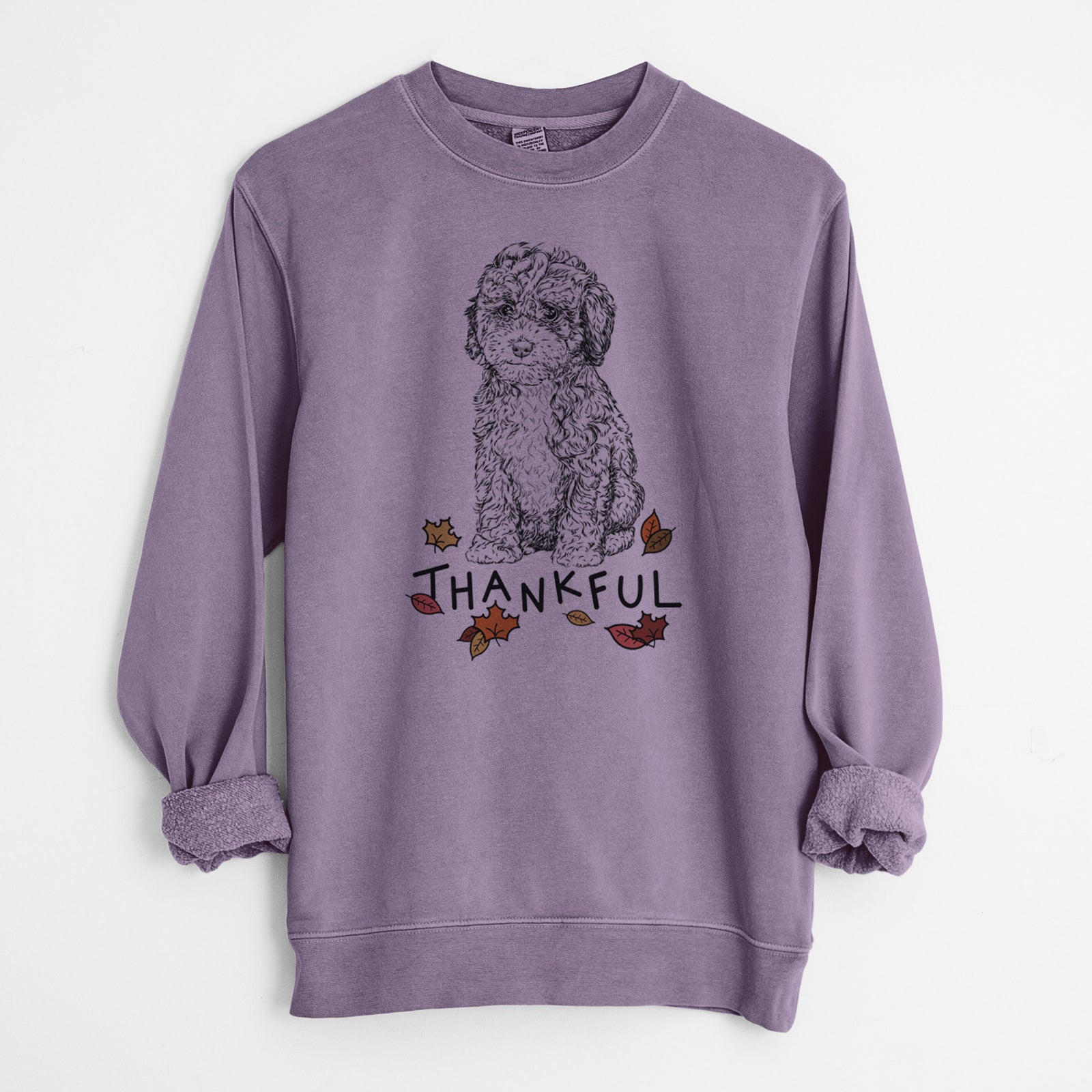 Hand-drawn sketch of Sweet Tea the Mini Doodle with 'Thankful' lettering and autumn leaves on a Plum Unisex pigment dyed crew sweatshirt