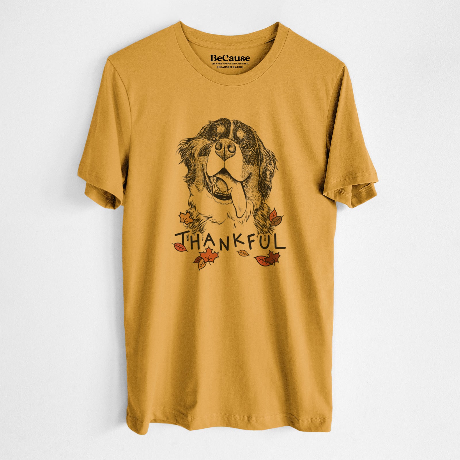 Hand-drawn sketch of Theo the Bernese Mountain Dog with 'Thankful' lettering and autumn leaves on a Mustard Unisex crewneck, worn by a man