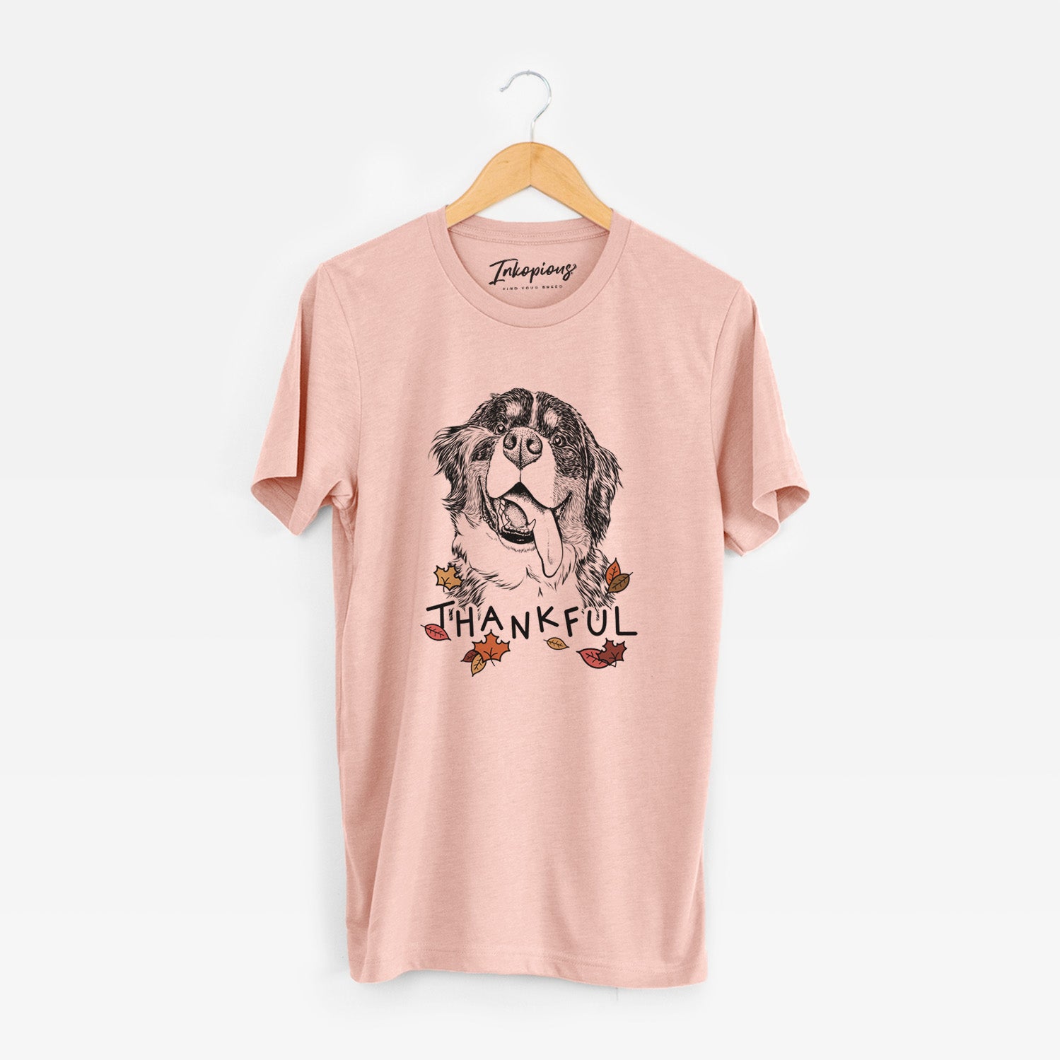 Hand-drawn sketch of Theo the Bernese Mountain Dog with 'Thankful' lettering and autumn leaves on a Peach Unisex crewneck