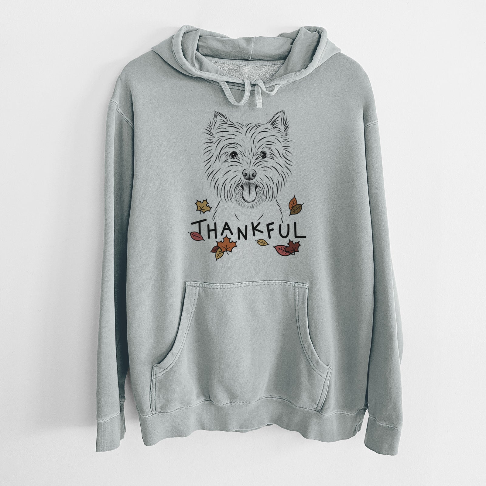 Hand-drawn sketch of Welma the West Highland Terrier with 'Thankful' lettering and autumn leaves on a Sage Unisex pigment dyed hoodie