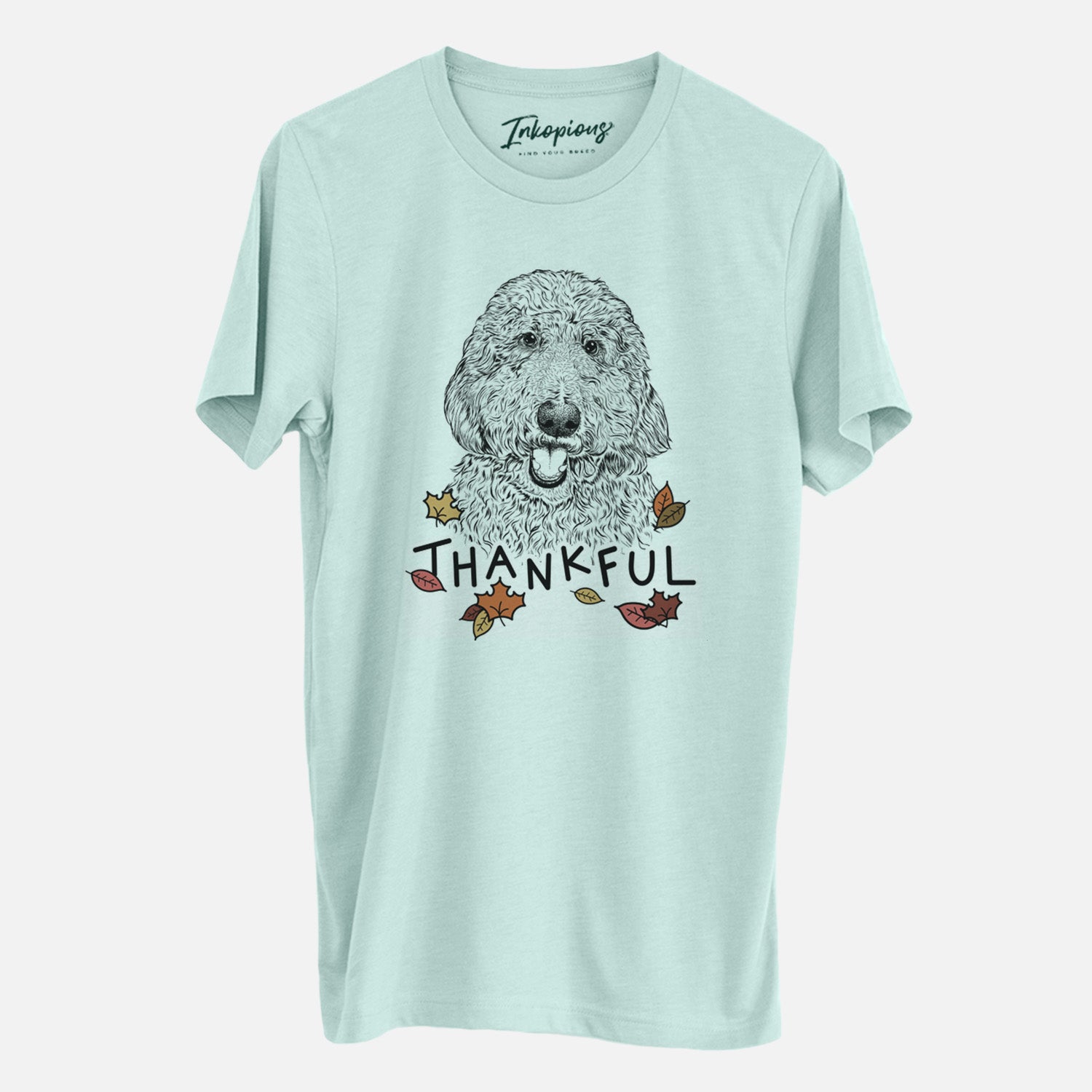 Hand-drawn sketch of Whisper the Goldendoodle with 'Thankful' lettering and autumn leaves on a Heather Sage Unisex crewneck