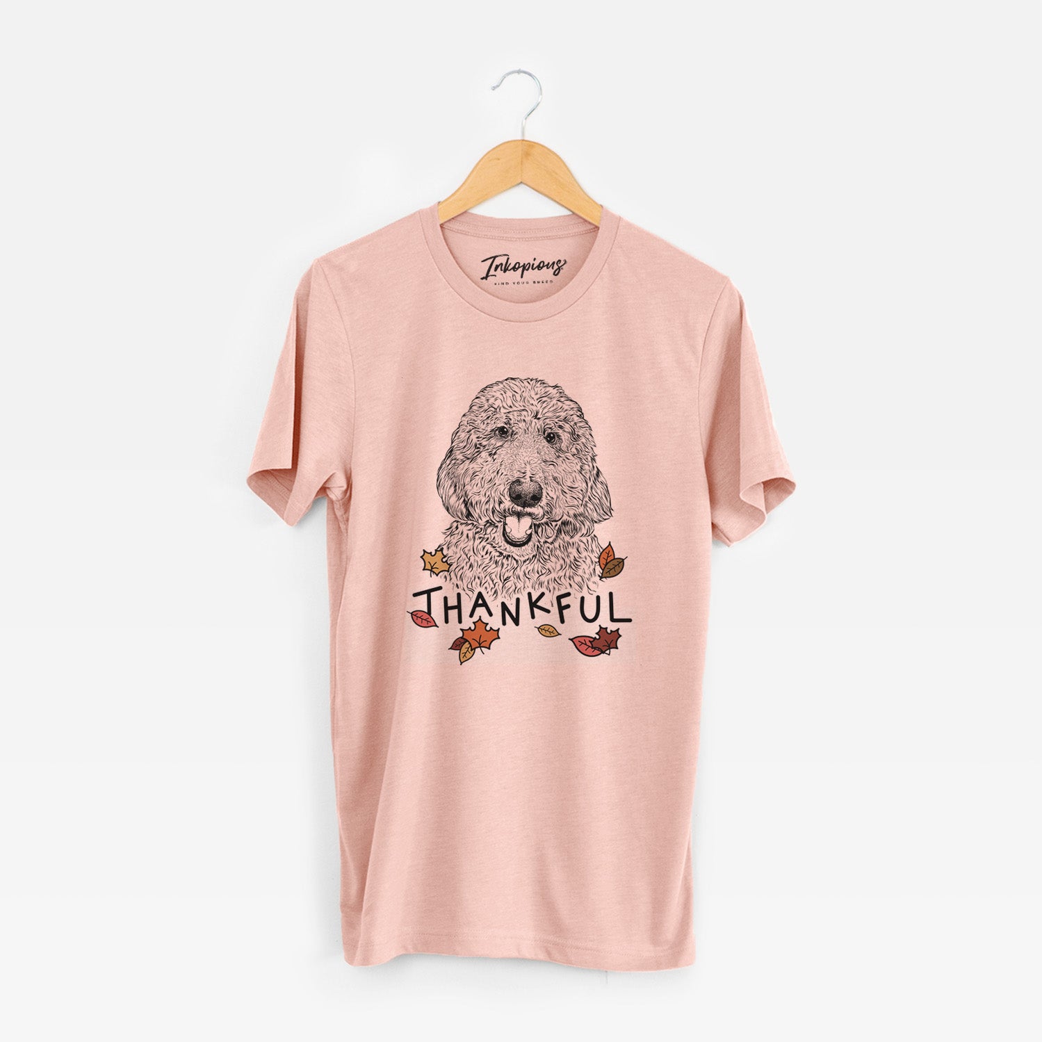 Hand-drawn sketch of Whisper the Goldendoodle with 'Thankful' lettering and autumn leaves on a Peach Unisex crewneck