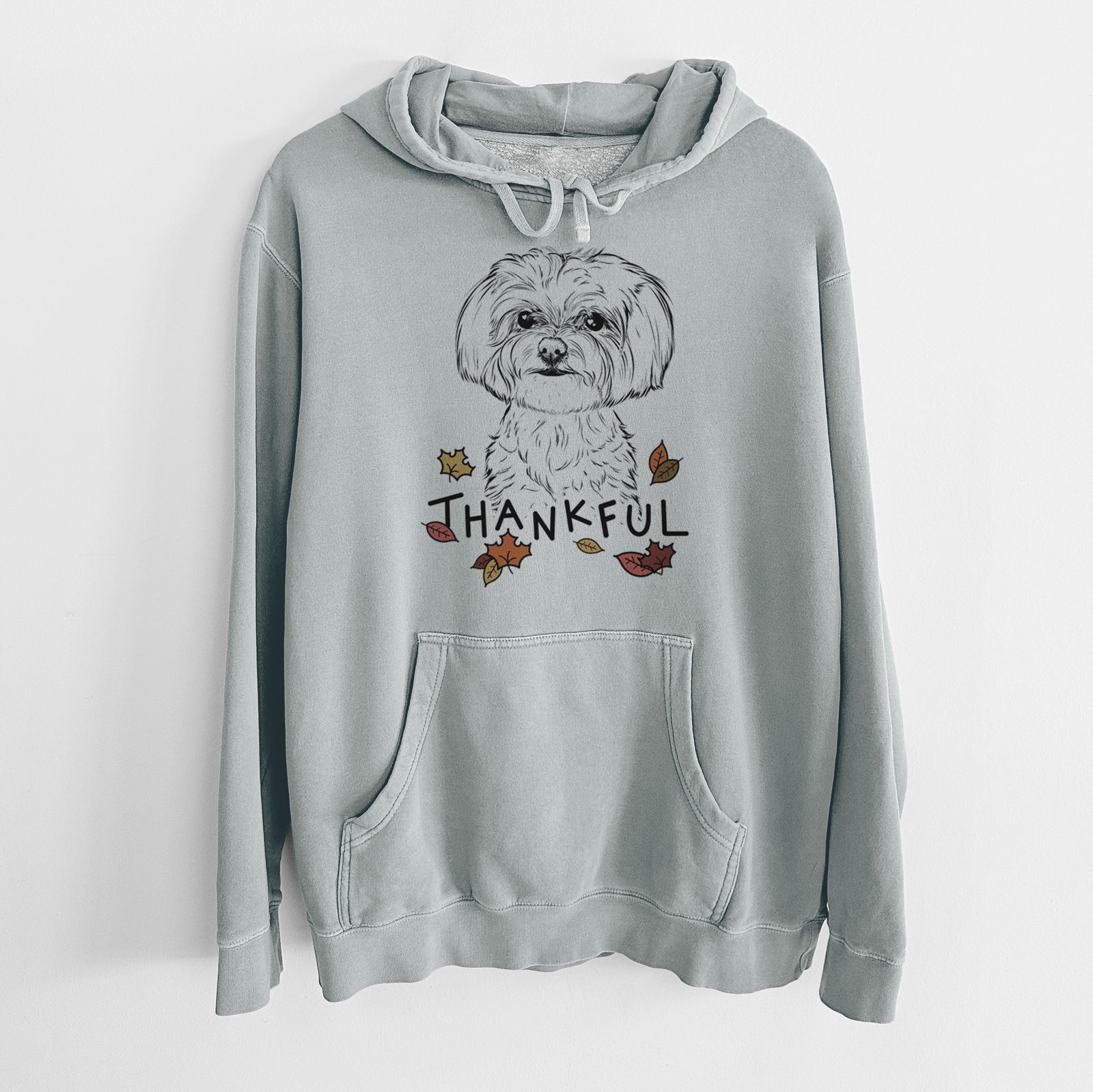 Hand-drawn sketch of Willow the Maltese with 'Thankful' lettering and autumn leaves on a Sage Unisex pigment dyed hoodie