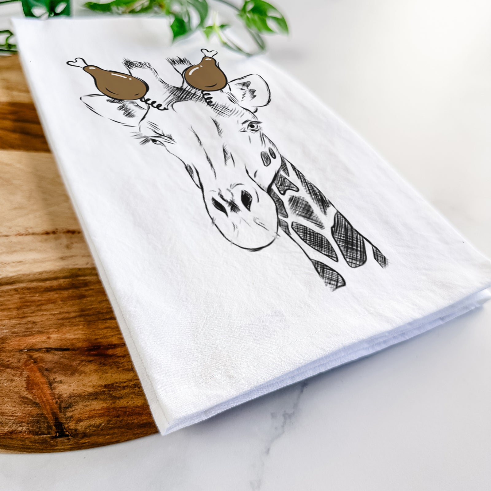 Hand-drawn sketch of Geoffrey the Giraffe with a Thanksgiving turkey headpiece on a tea towel