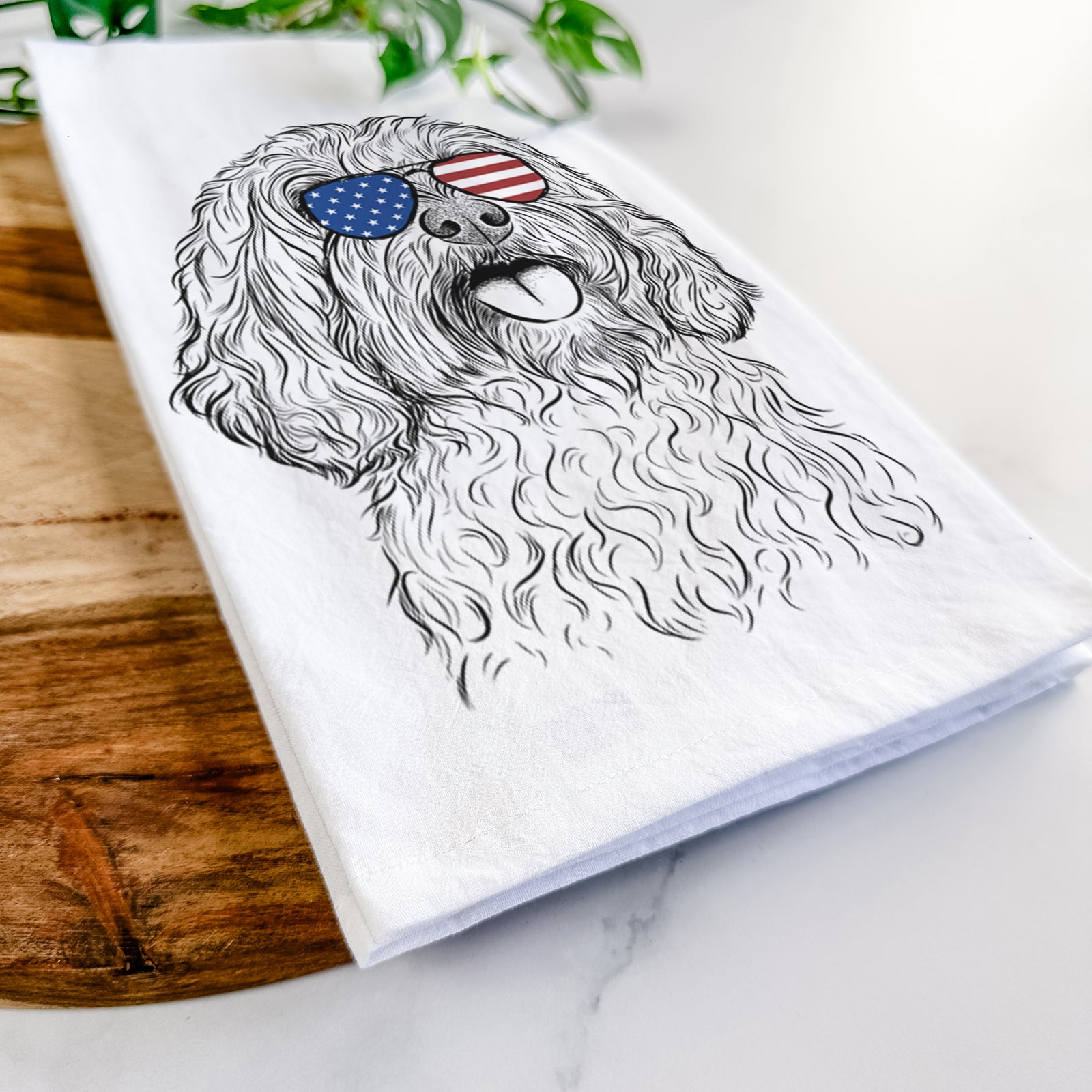 Hand-drawn sketch of Cali the Cavapoo wearing American flag sunglasses on a tea towel