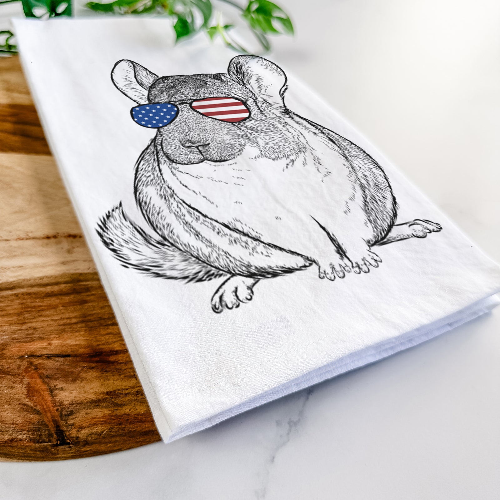 Hand-drawn sketch of Cheddar the Chinchilla wearing American flag sunglasses on a tea towel