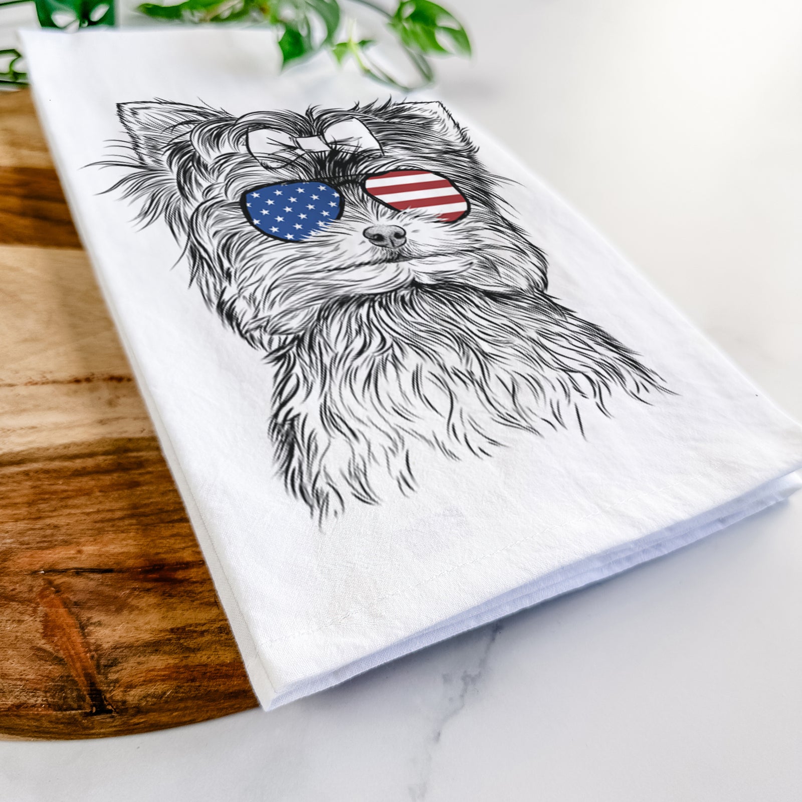 Hand-drawn sketch of Cricket the Biewer Terrier wearing American flag sunglasses on a tea towel