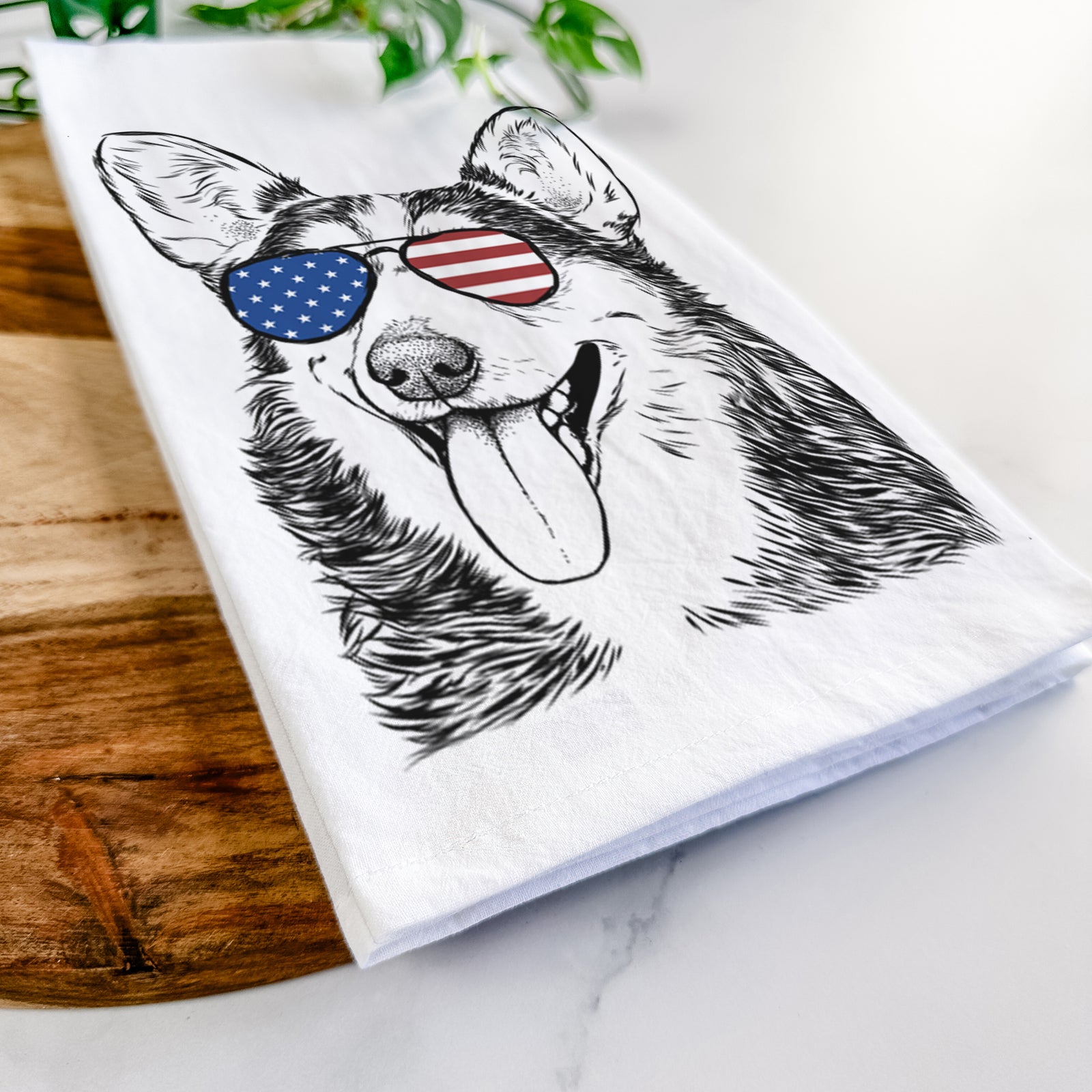 Hand-drawn sketch of Darma the Corgi wearing American flag sunglasses on a tea towel