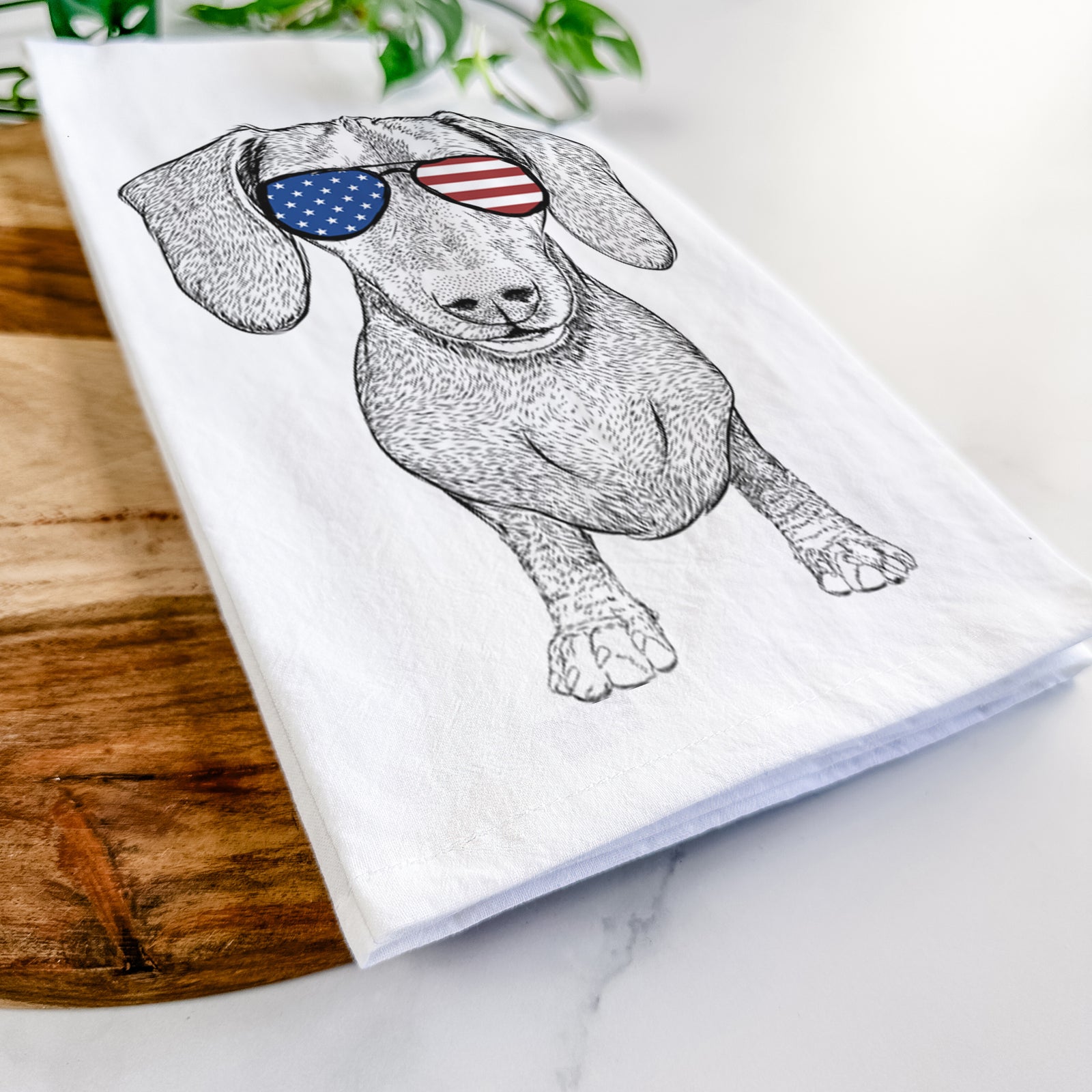 Hand-drawn sketch of Ernie the Mini Dachshund wearing American flag sunglasses on a tea towel