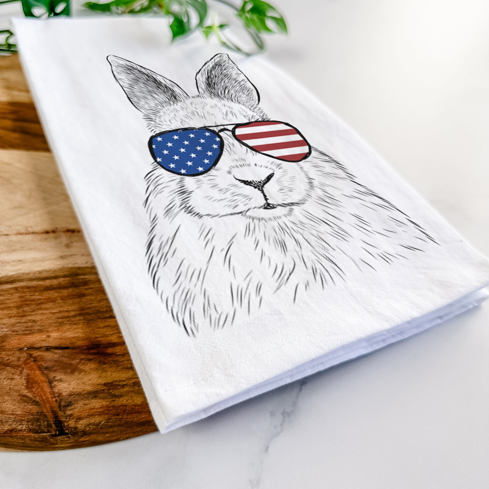 Hand-drawn sketch of Flower the Rex Rabbit wearing American flag sunglasses on a tea towel
