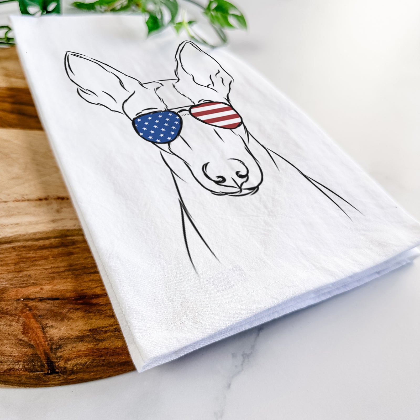Hand-drawn sketch of Indy the Ibizan Hound wearing American flag sunglasses on a tea towel