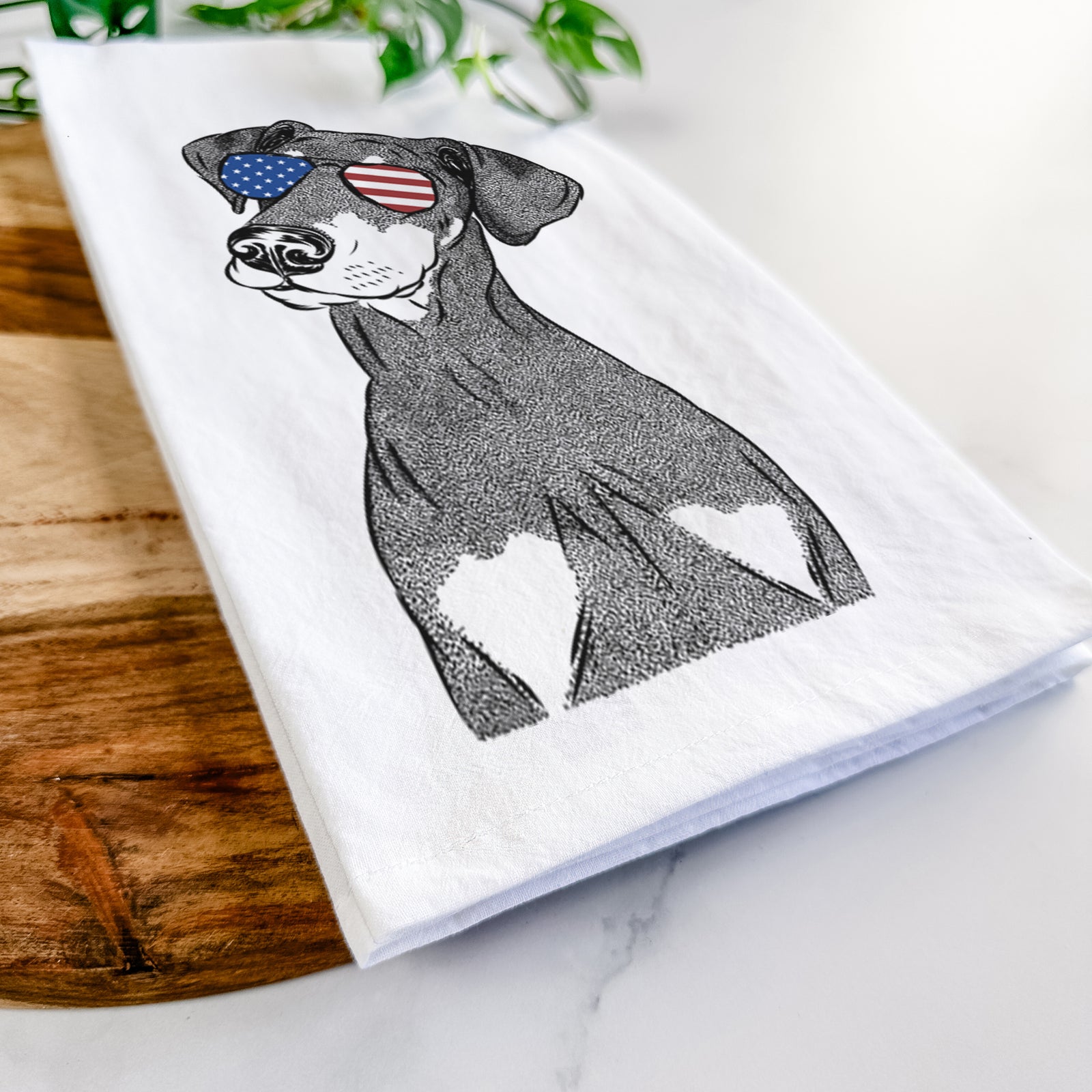 Hand-drawn sketch of Iroh the Doberman Pinscher wearing American flag sunglasses on a tea towel