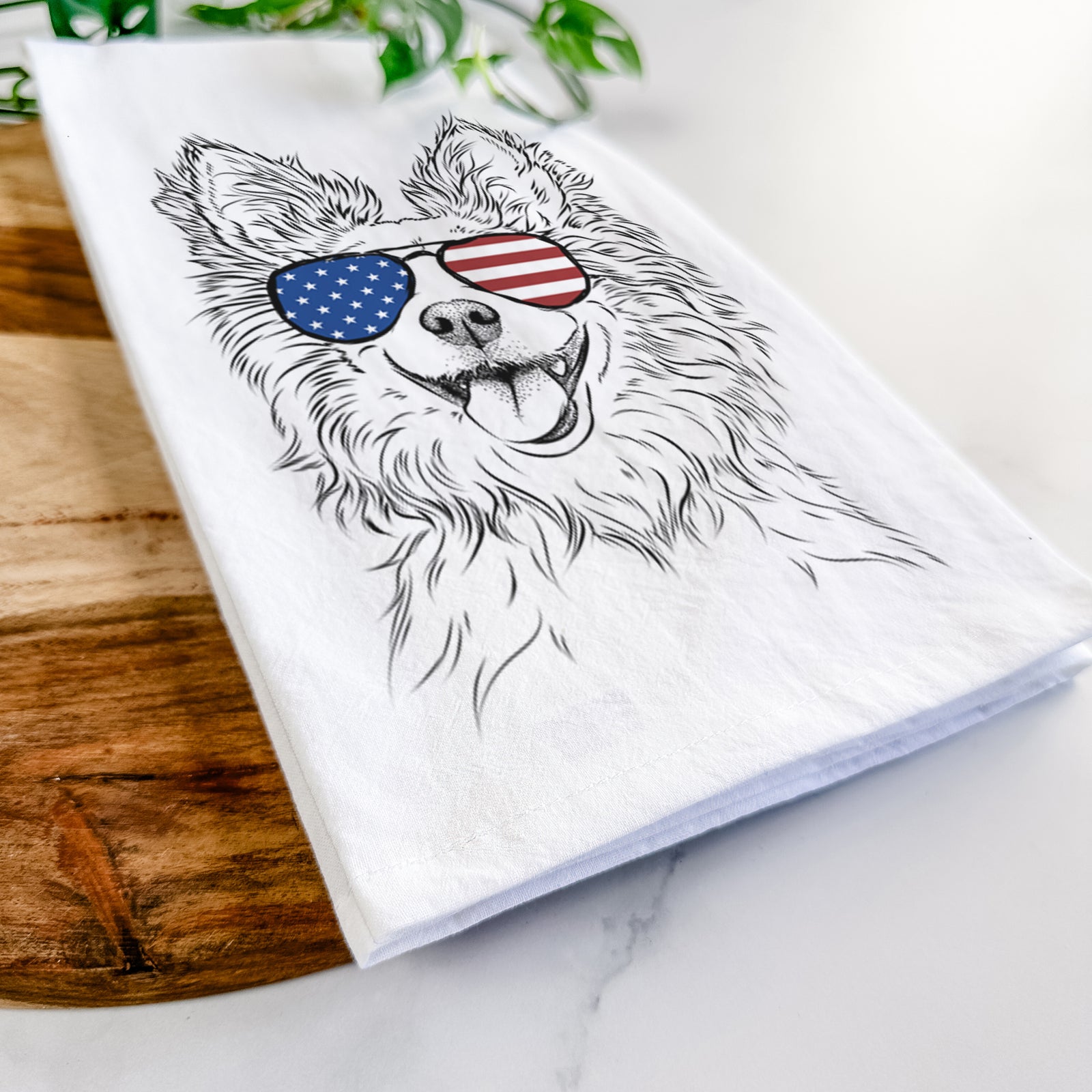 Hand-drawn sketch of Jasper the Pomchi wearing American flag sunglasses on a tea towel