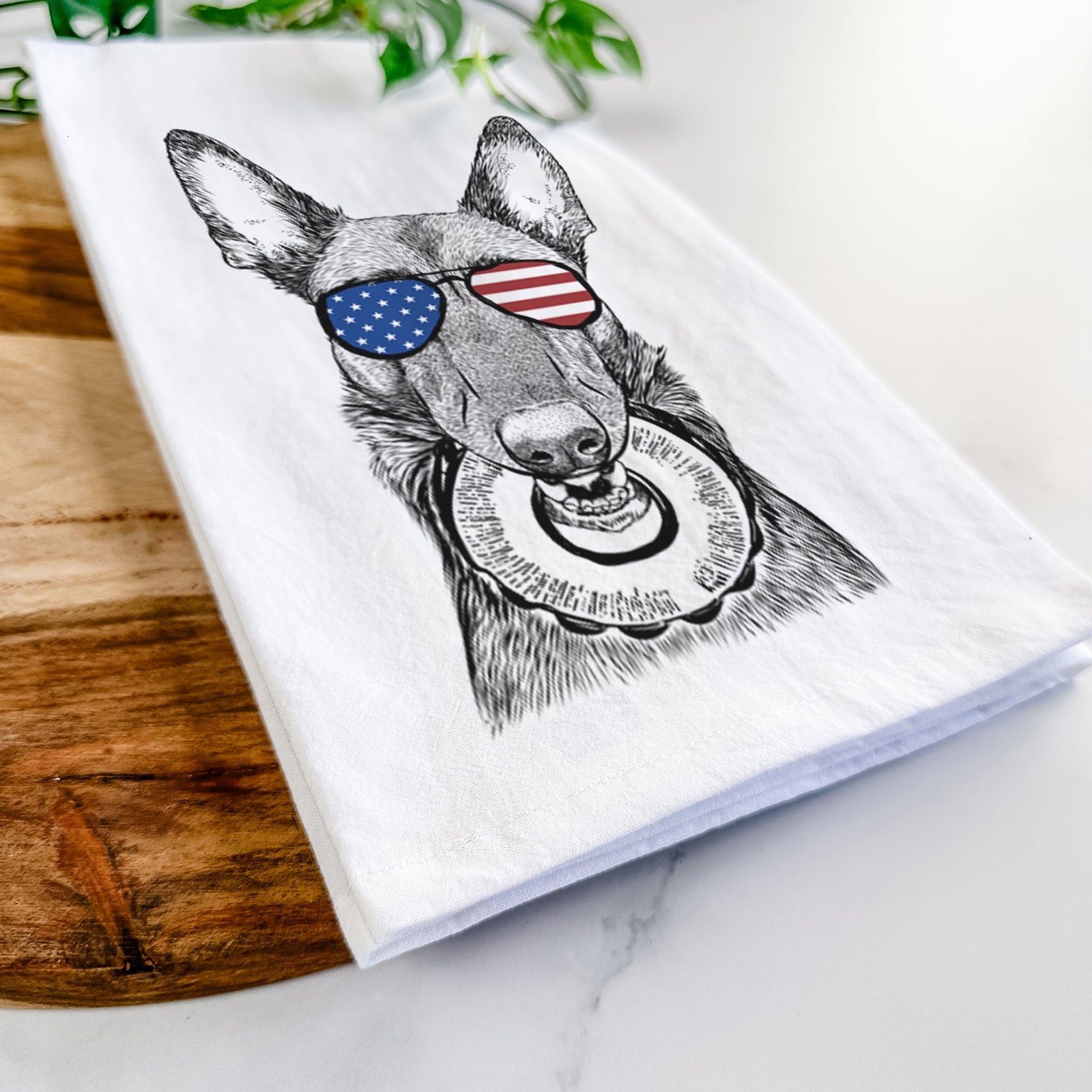 Hand-drawn sketch of Juno the Belgian Malinois wearing American flag sunglasses on a tea towel