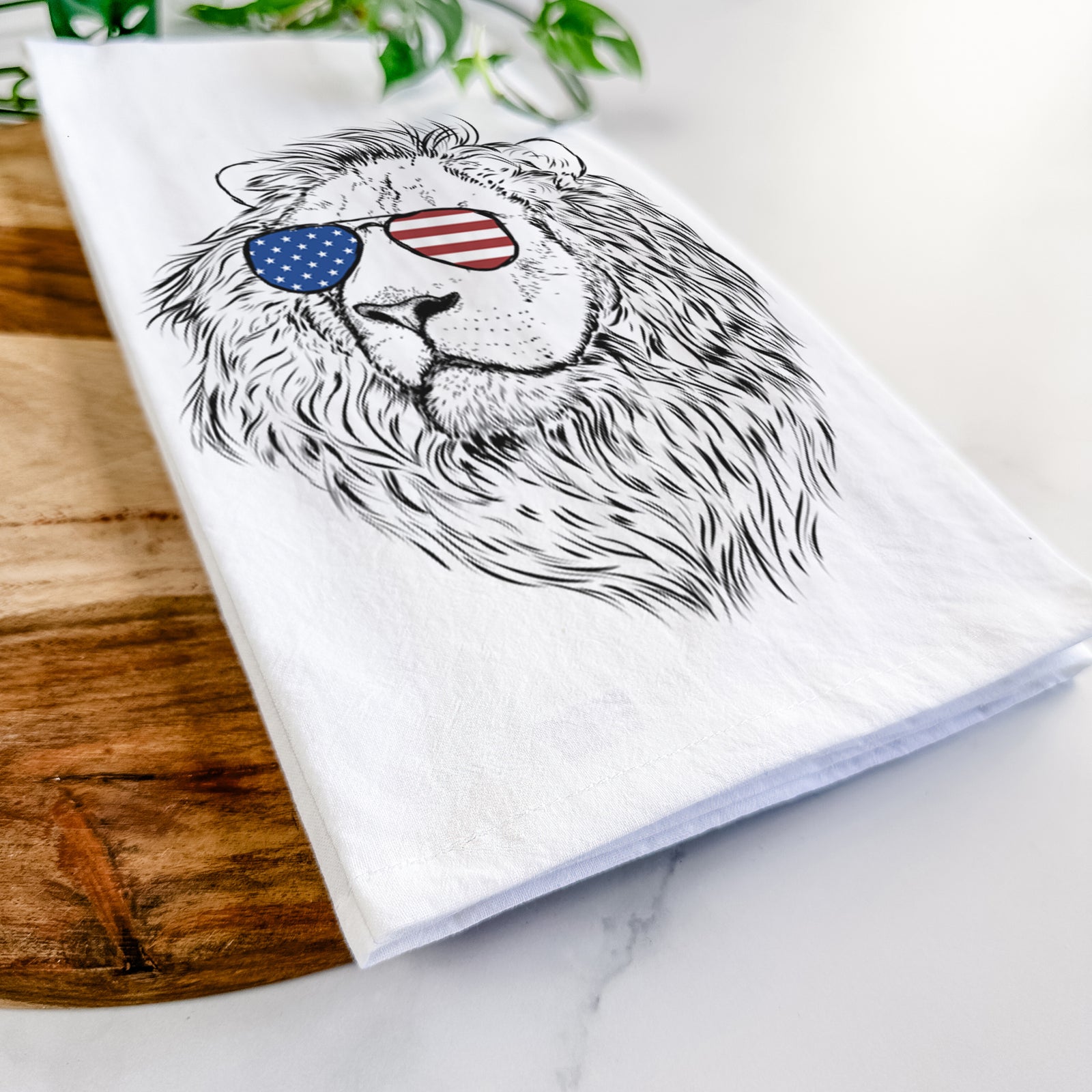 Hand-drawn sketch of Lenny the Lion wearing American flag sunglasses on a tea towel