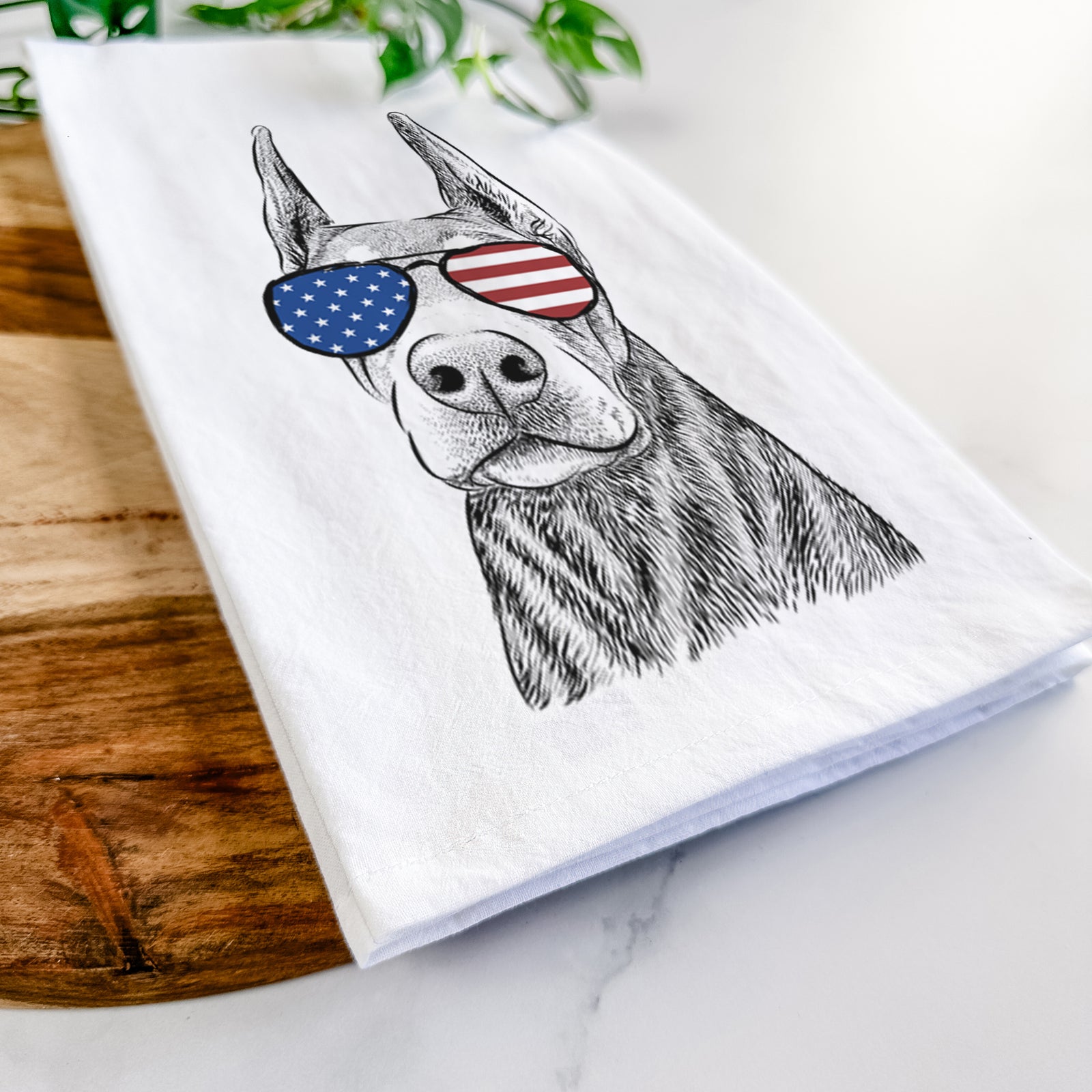 Hand-drawn sketch of Luna the Doberman Pinscher wearing American flag sunglasses on a tea towel