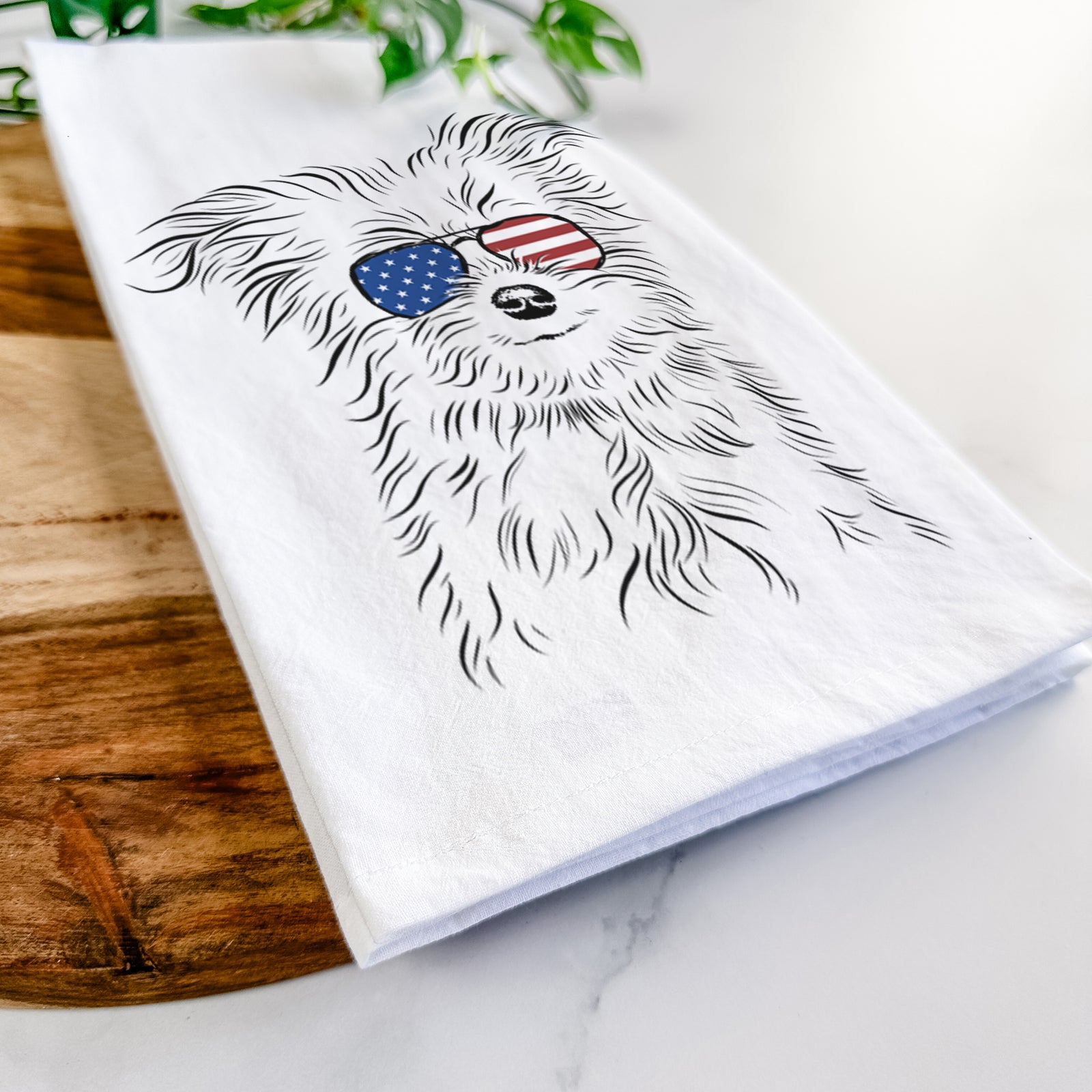 Hand-drawn sketch of Mr. Gucci Poochi the Maltese wearing American flag sunglasses on a tea towel