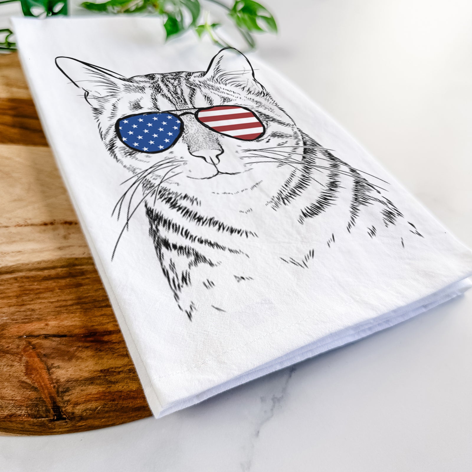 Hand-drawn sketch of Nell the Tabby Cat wearing American flag sunglasses on a tea towel