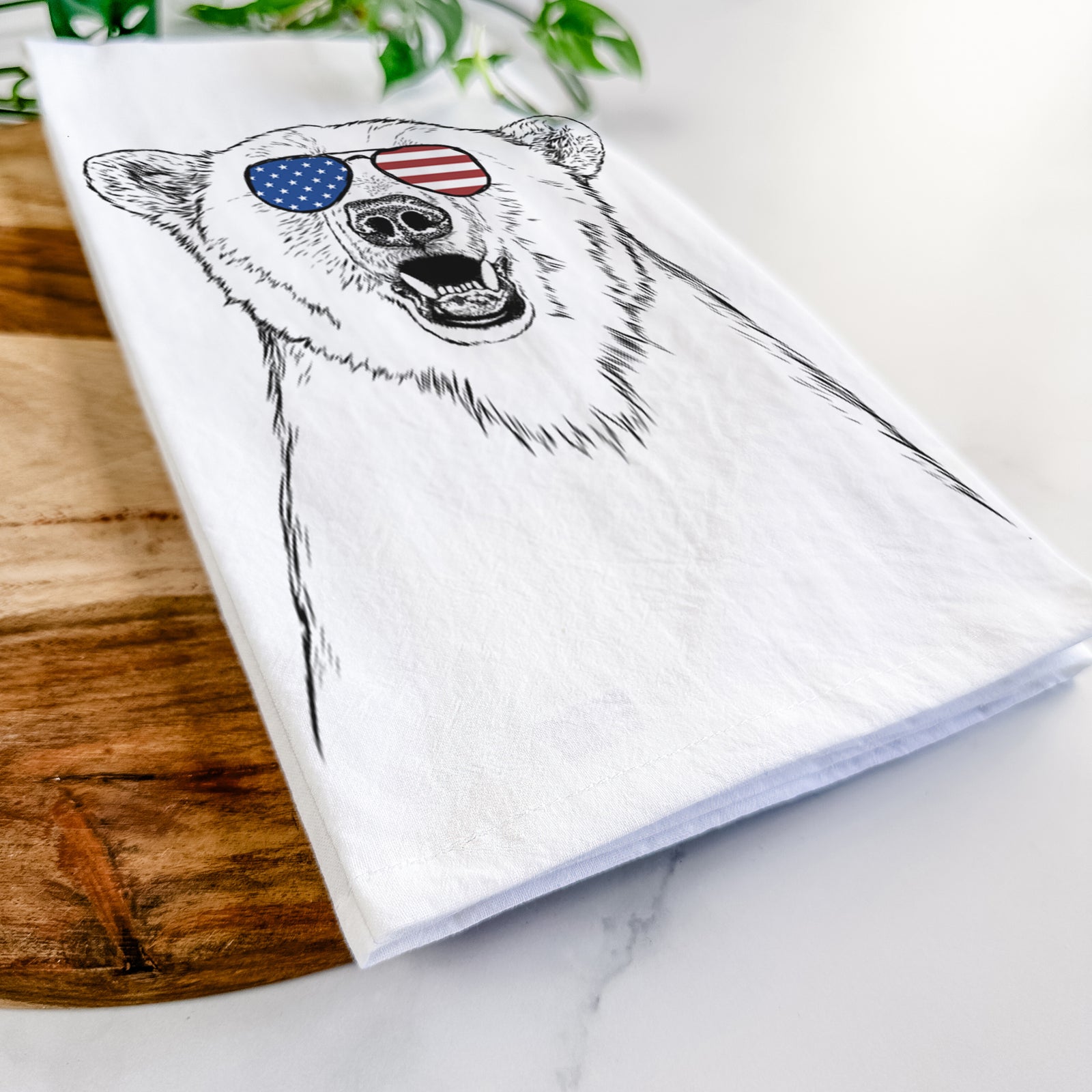 Hand-drawn sketch of Oslo the Polar Bear wearing American flag sunglasses on a tea towel