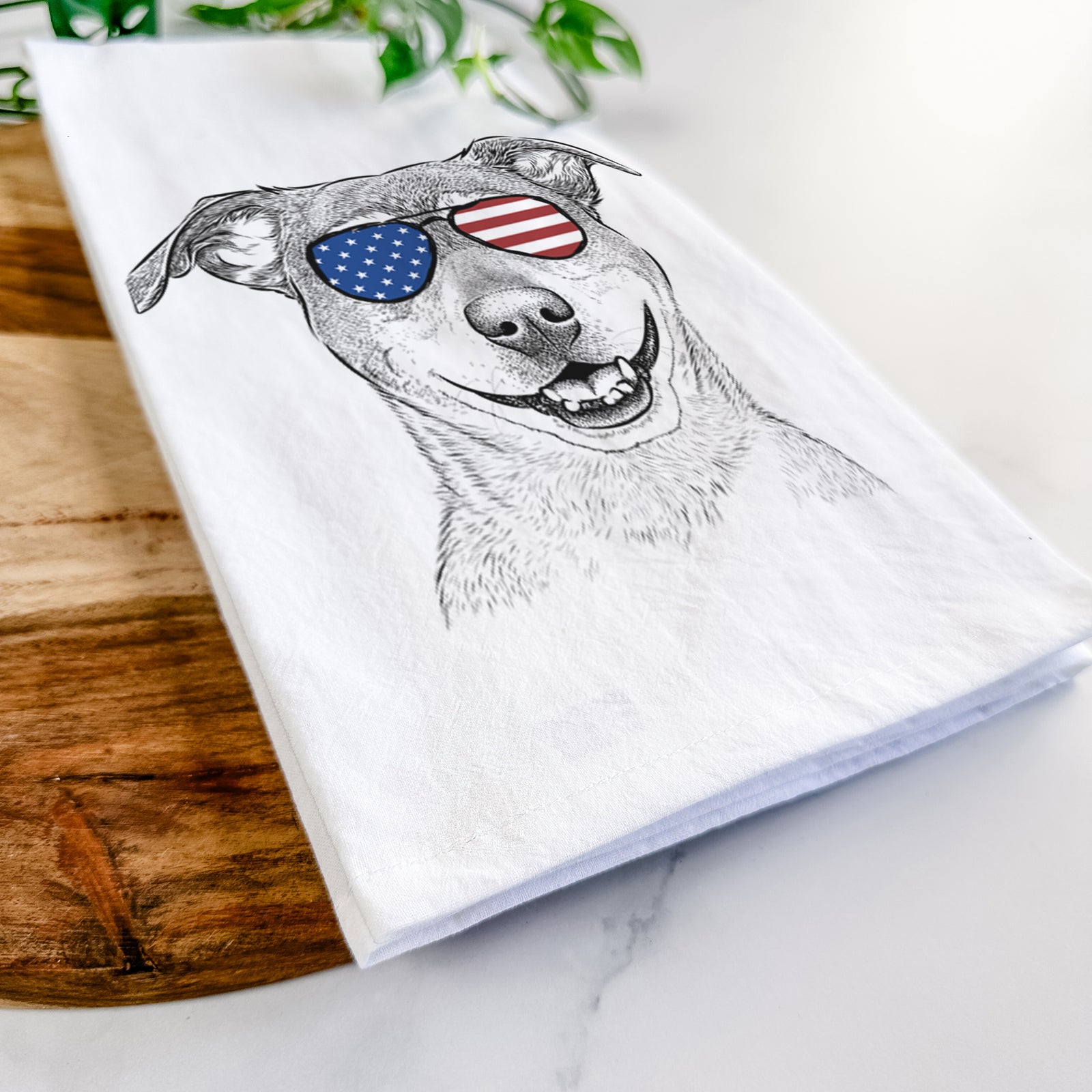 Hand-drawn sketch of Reese the Mountain Cur wearing American flag sunglasses on a tea towel