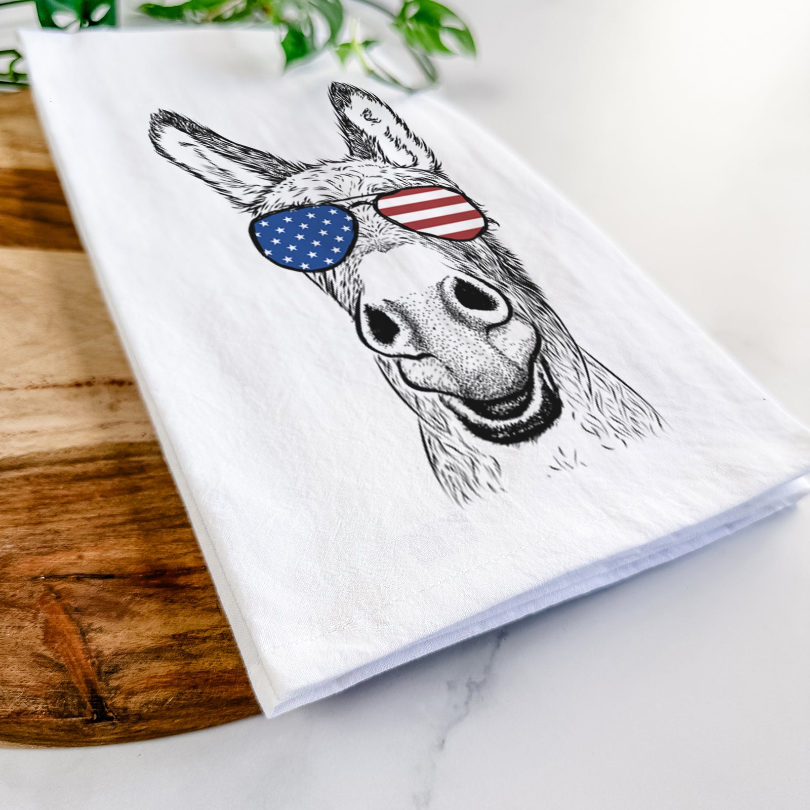 Hand-drawn sketch of Samule the Donkey wearing American flag sunglasses on a tea towel