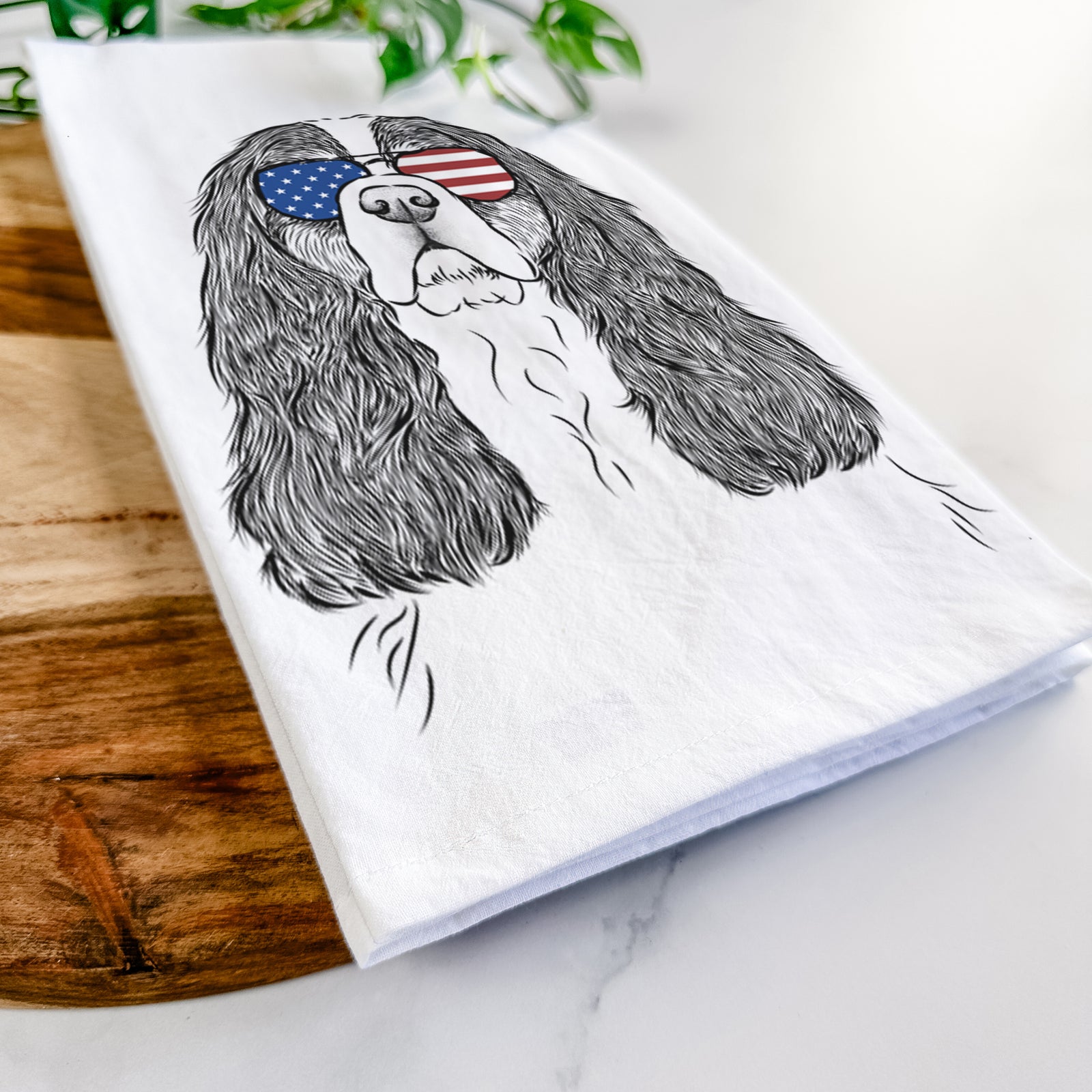 Hand-drawn sketch of Sebastian the Cavalier King Charles Spaniel wearing American flag sunglasses on a tea towel