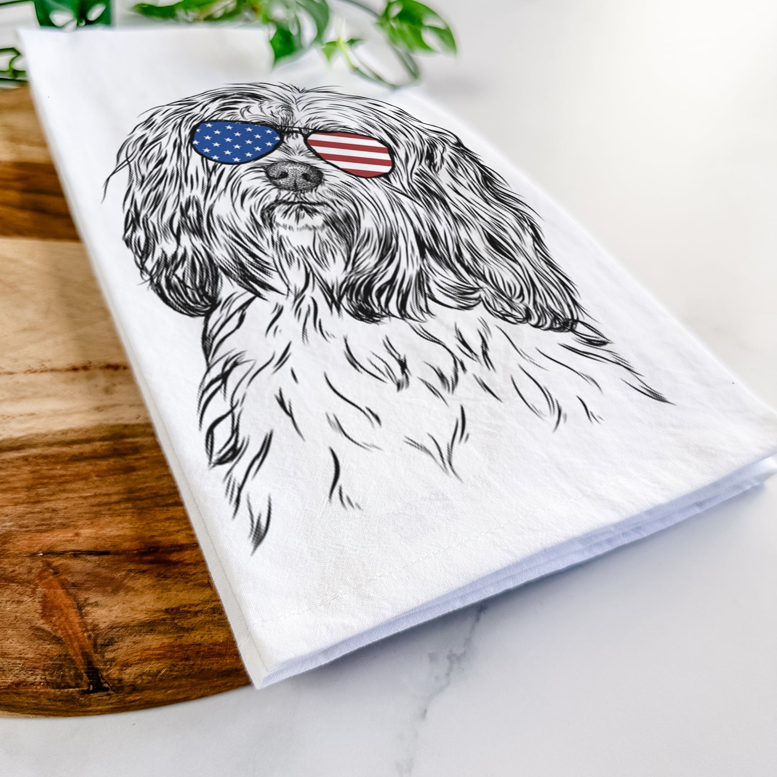 Hand-drawn sketch of Shenpa the Tibetan Terrier wearing American flag sunglasses on a tea towel