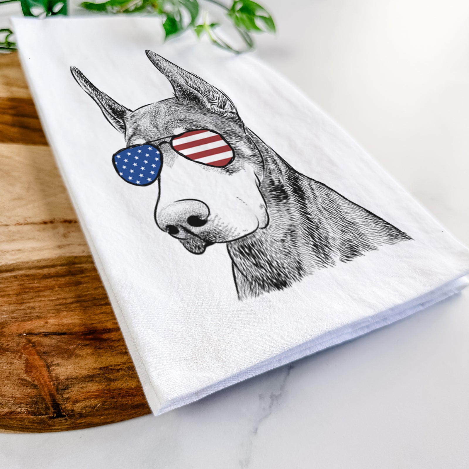 Hand-drawn sketch of Sunny the Doberman Pinscher wearing American flag sunglasses on a tea towel
