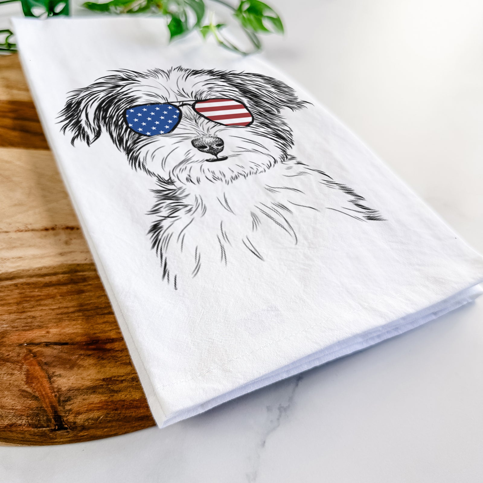 Hand-drawn sketch of Teddy the Havanese wearing American flag sunglasses on a tea towel
