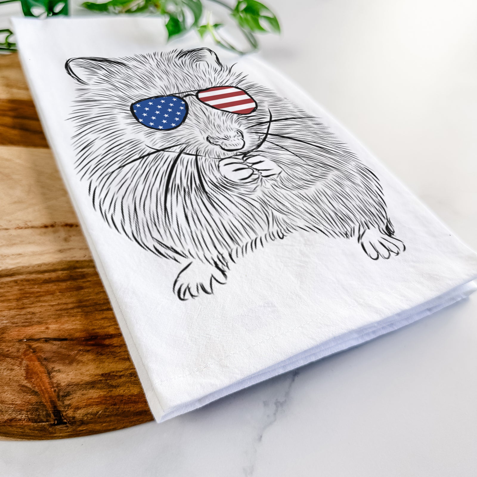 Hand-drawn sketch of Twitch the Hamster wearing American flag sunglasses on a tea towel