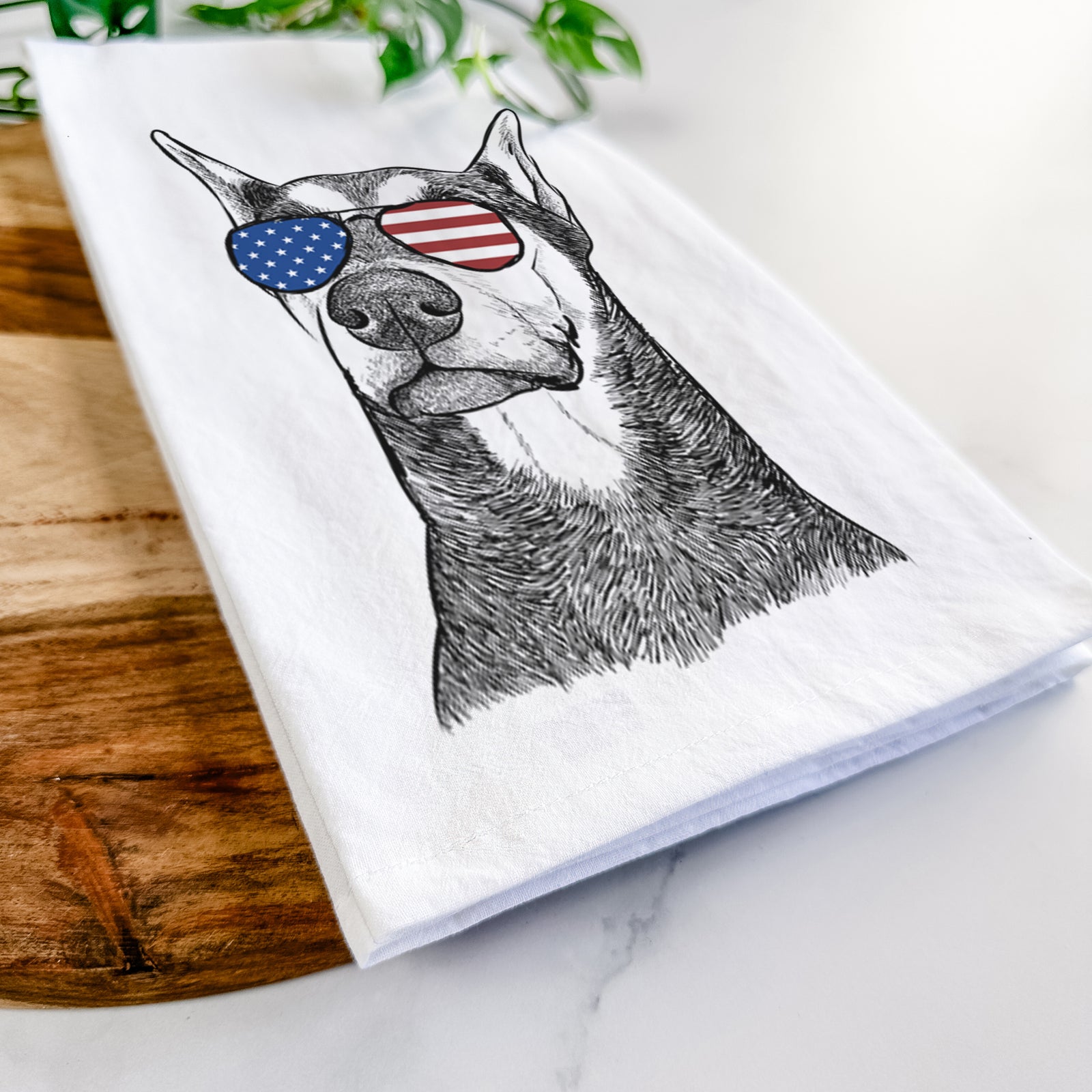 Hand-drawn sketch of Zeus the Doberman Pinscher wearing American flag sunglasses on a tea towel